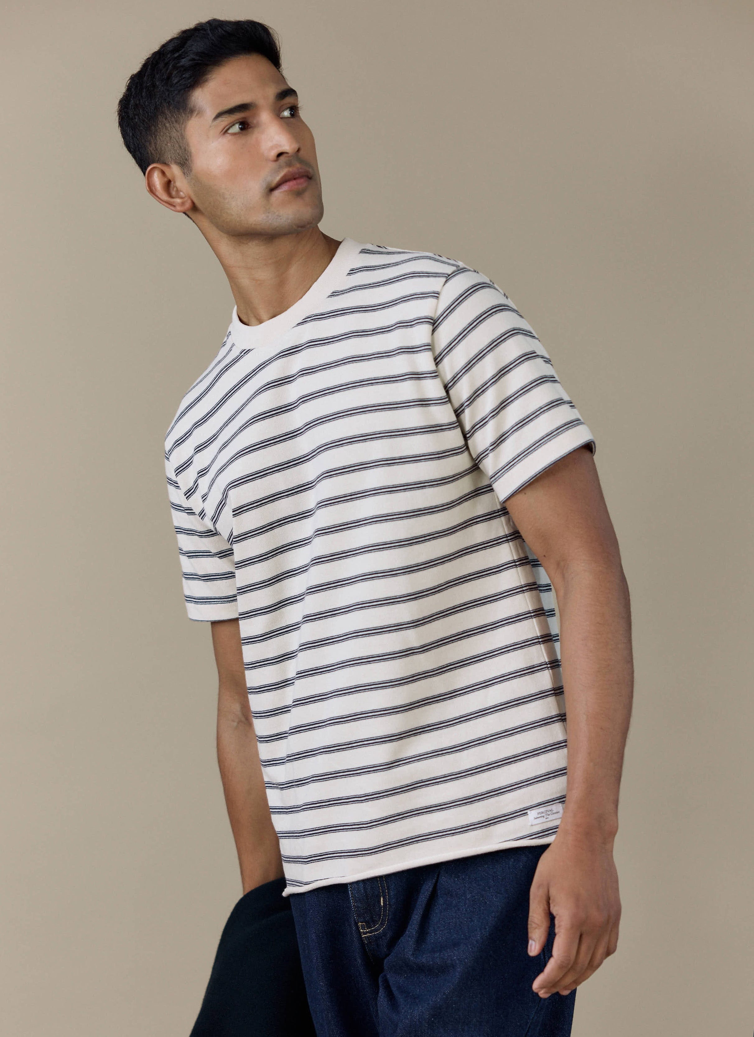 A model wears the Percival Arlo Raw Hem Breton T Shirt in white stripe, an organic cotton tee with classic navy stripes.