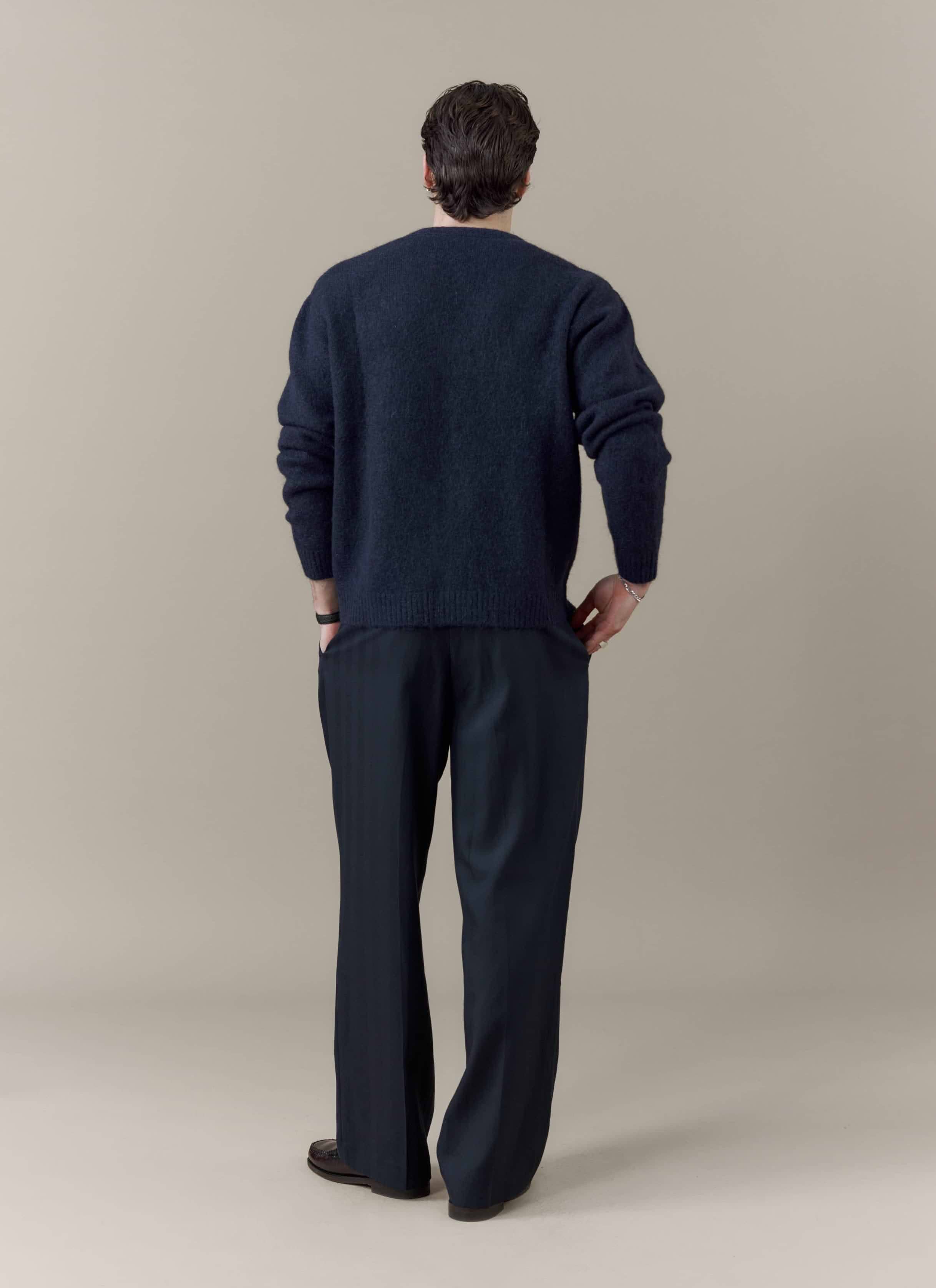 Rear view of a model wearing the navy White Glove Cardigan from the Percival x Brighton & Hove Albion F.C. collaboration.