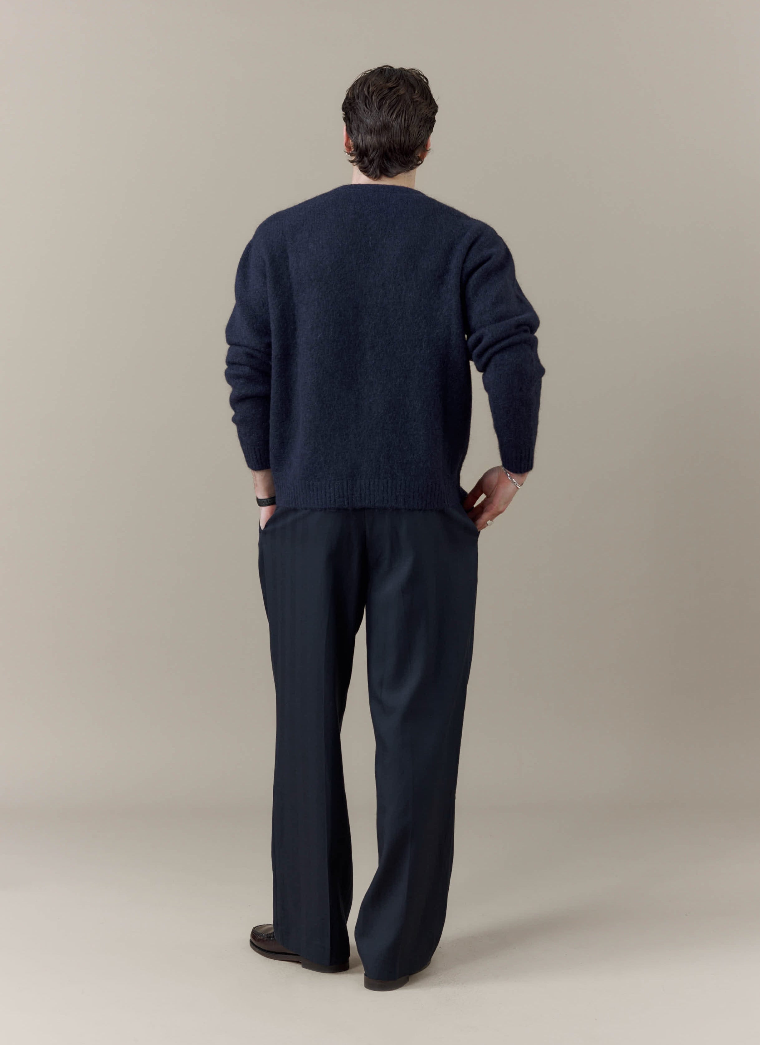 Rear view of a model wearing the navy White Glove Cardigan from the Percival x Brighton & Hove Albion F.C. collaboration.
