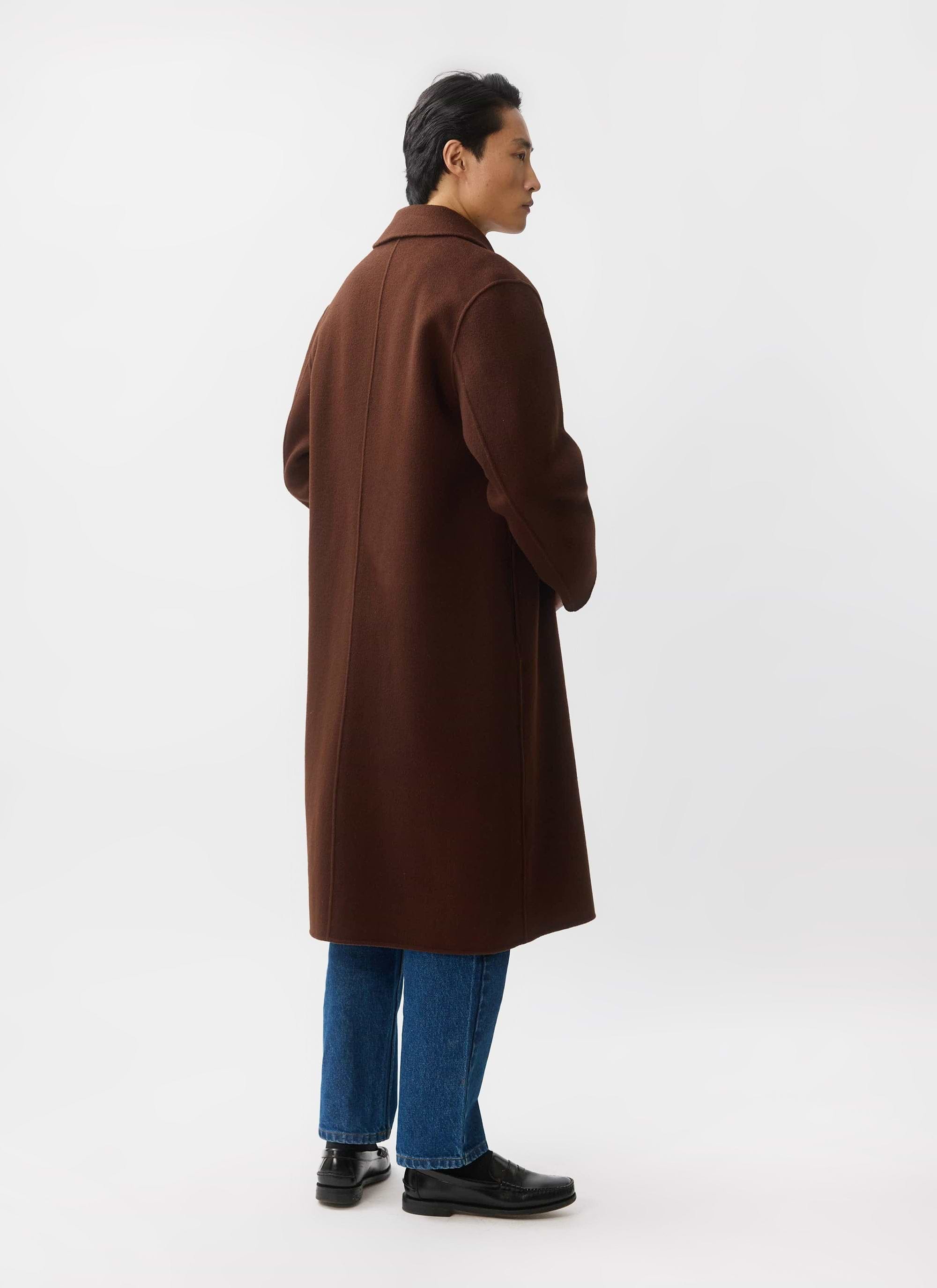 The back profile of a model wearing the Percival Minnesota Overcoat in espresso wool over blue jeans.