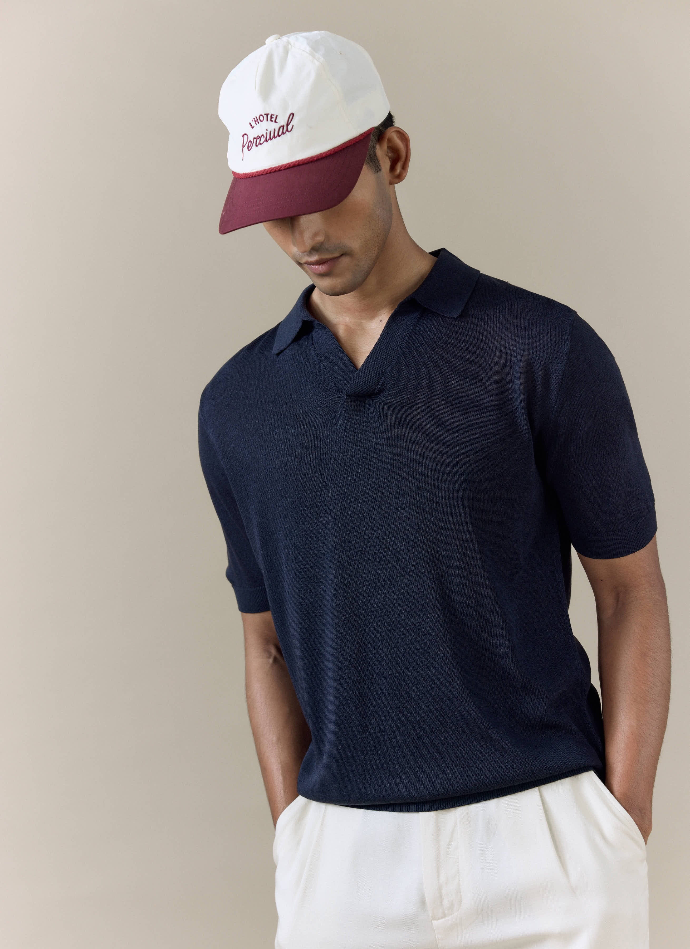 Model wearing the navy Percival Laurence Knitted Polo in a breathable linen blend, featuring an open V placket.