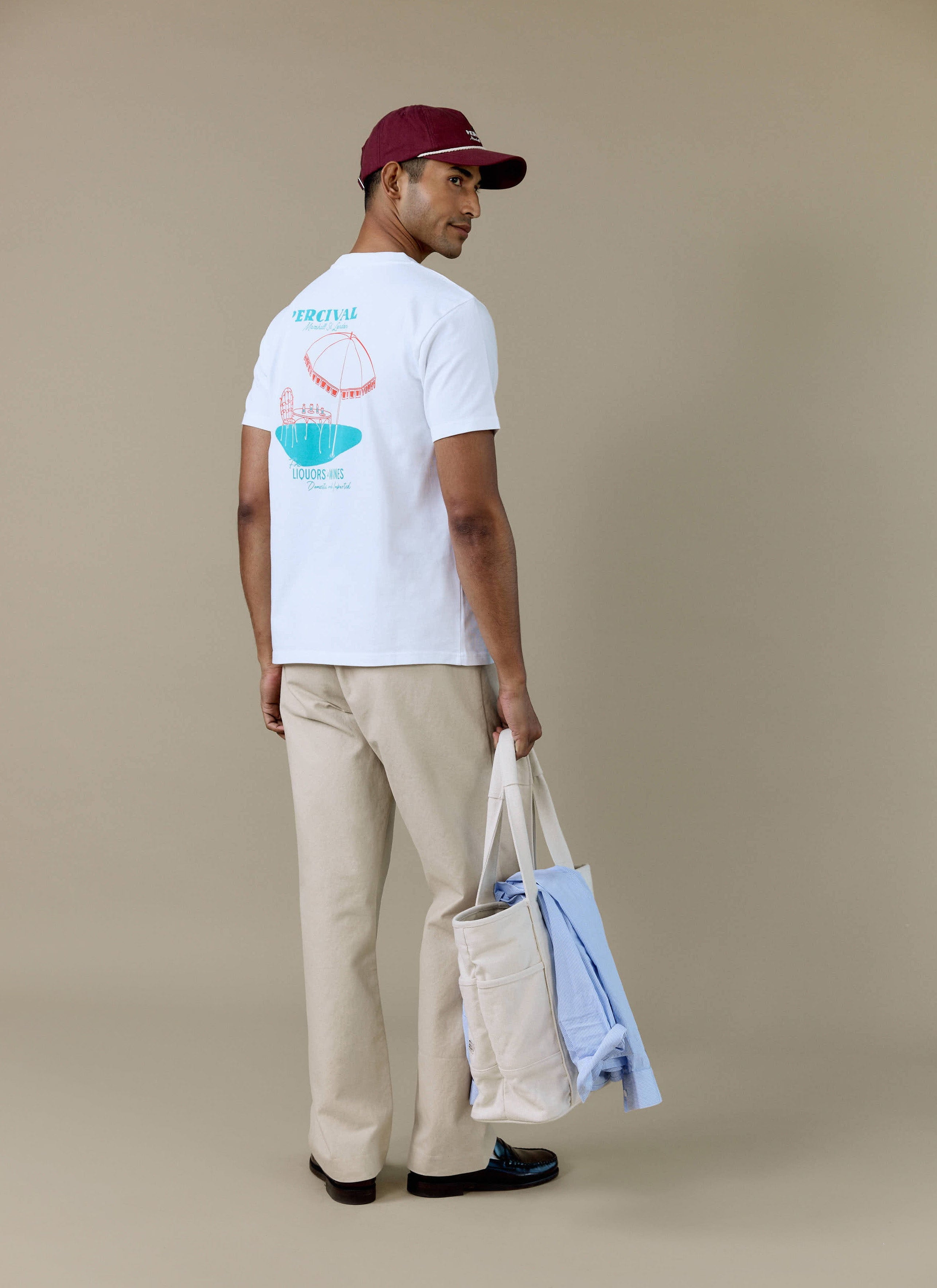 Rear view of a model wearing the white Percival Perci Fine Wines T-shirt, featuring the illustrated back graphic.