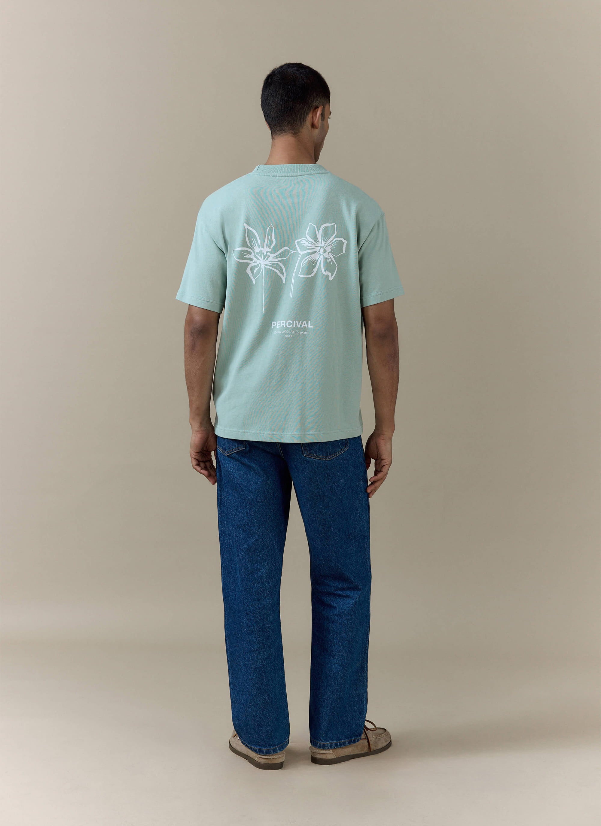 Rear view of the Percival Melvin Oversized T Shirt in sage organic cotton, featuring a white floral back graphic.