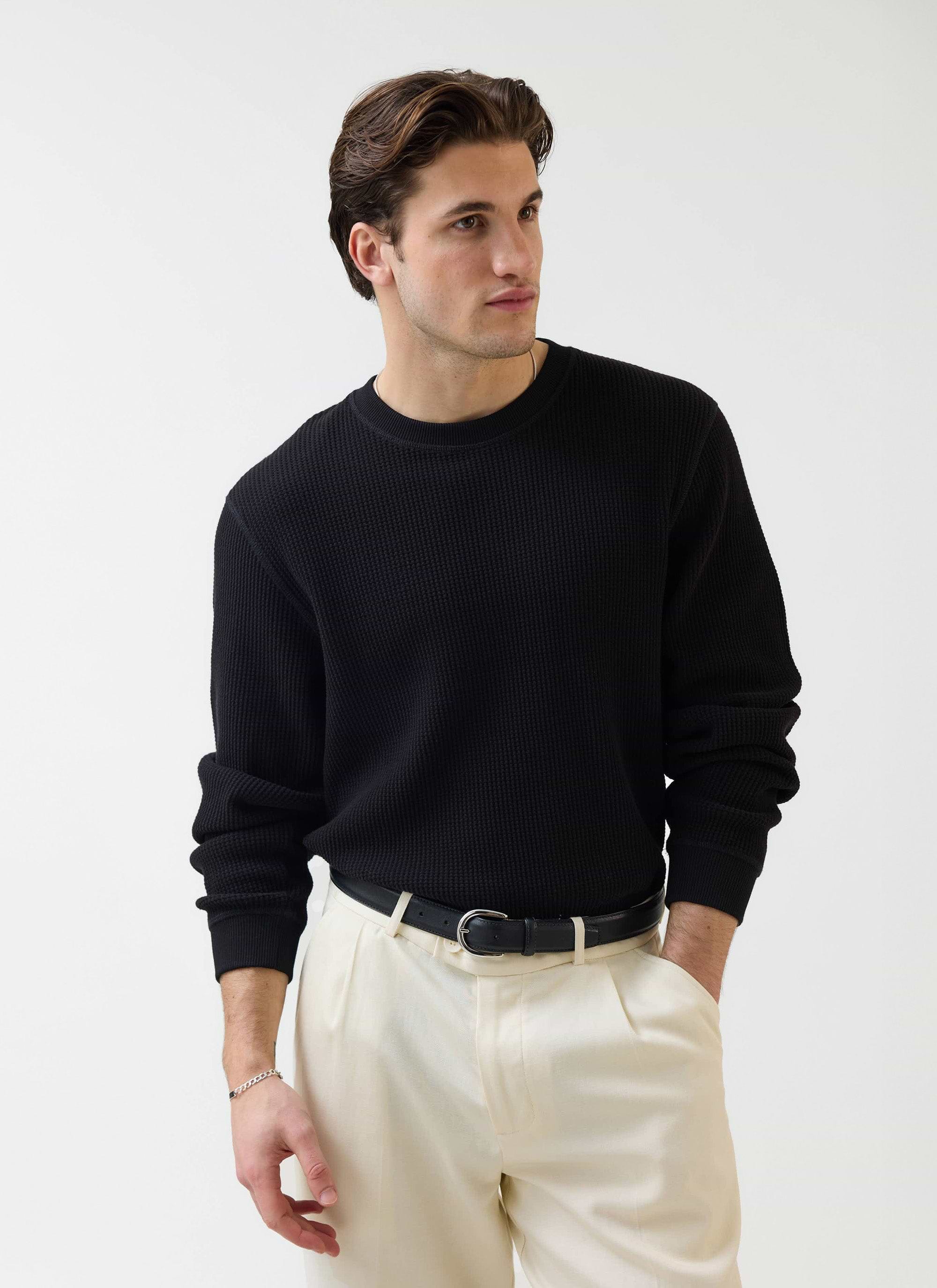 A model wears the Percival black Waffle Long Sleeve T-Shirt, styled with cream trousers against a white studio background.