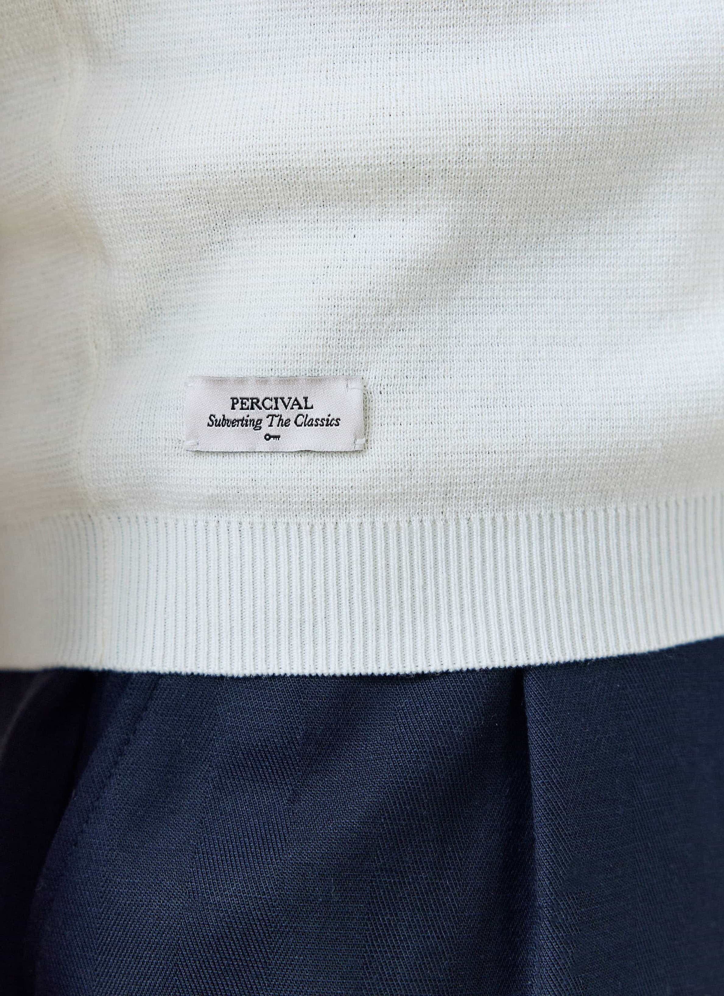 Close-up of the cream Percival Laurence Knitted Polo hem, showing the branded tab and fine linen-blend knit.