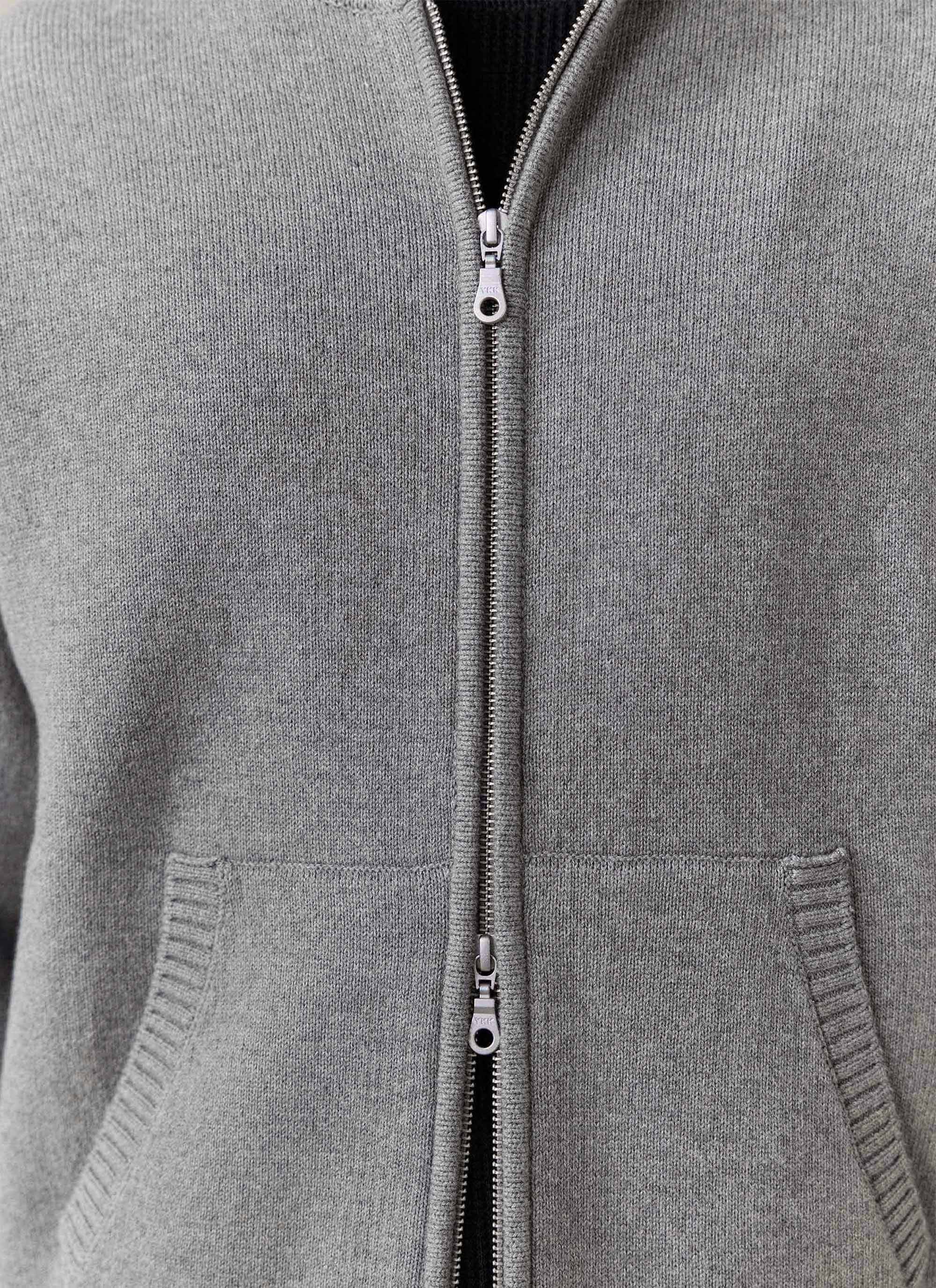 A close-up of the grey Chronicle Knitted Hoodie from Percival, showing the two-way zip, knit texture, and kangaroo pocket.