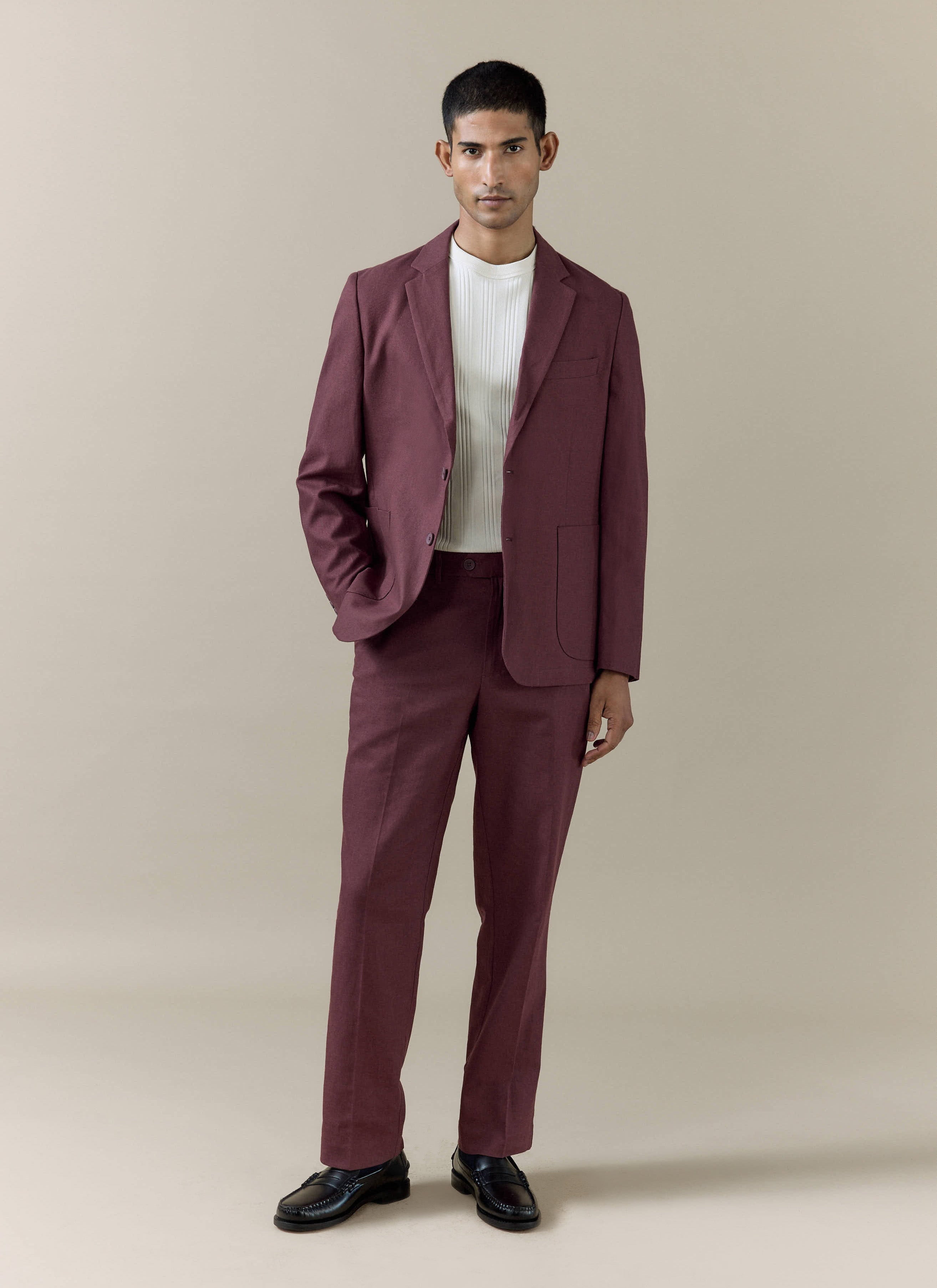 Model wearing the Percival tailored linen blazer and matching trousers in merlot with a white ribbed shirt.