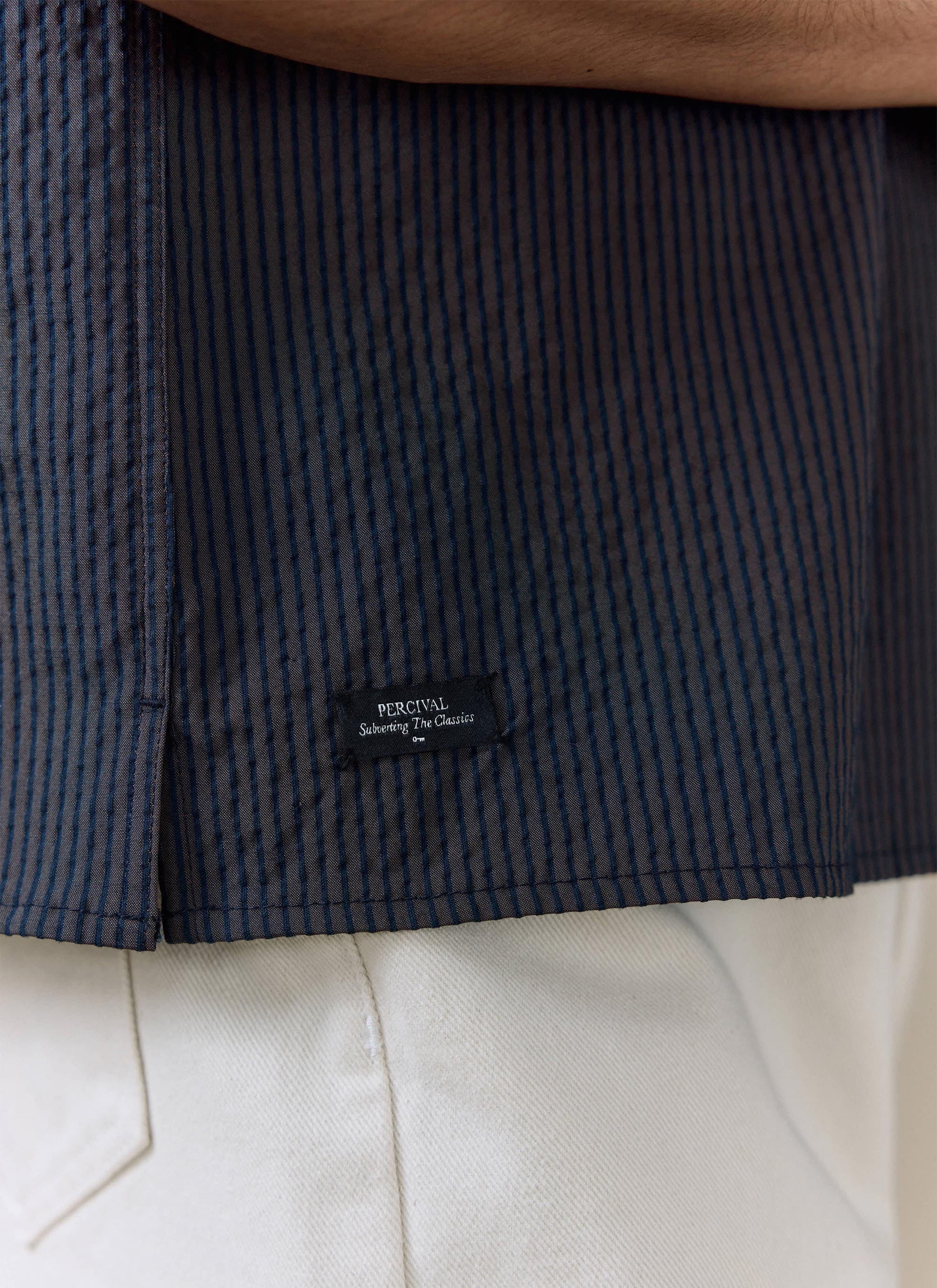 Close-up of the navy stripe seersucker cotton on the Percival Rowan Boxy Shirt, featuring the woven brand label.