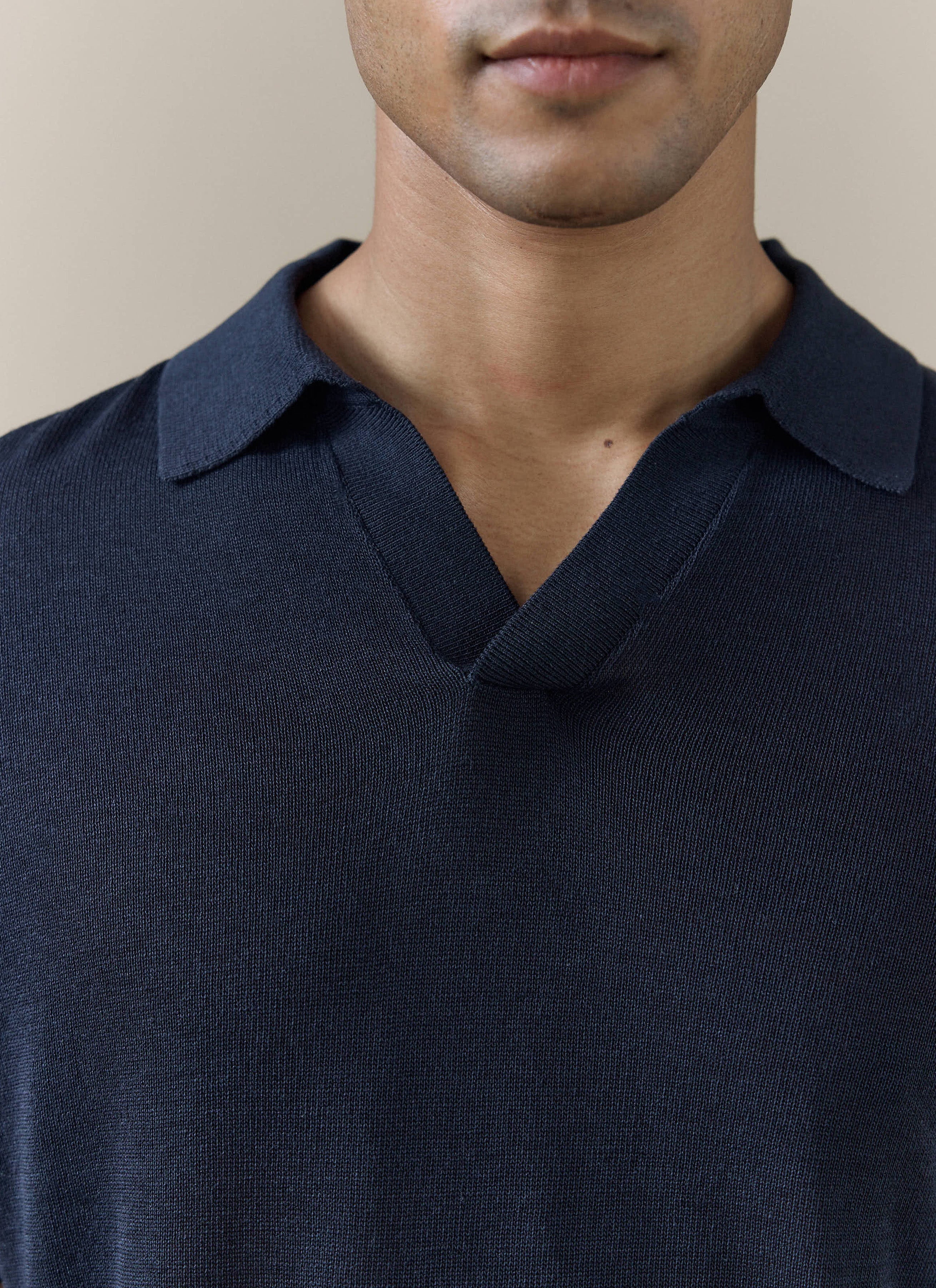 Close-up of the navy Percival Laurence Knitted Polo, showing the refined V placket and breathable linen lyocell blend.