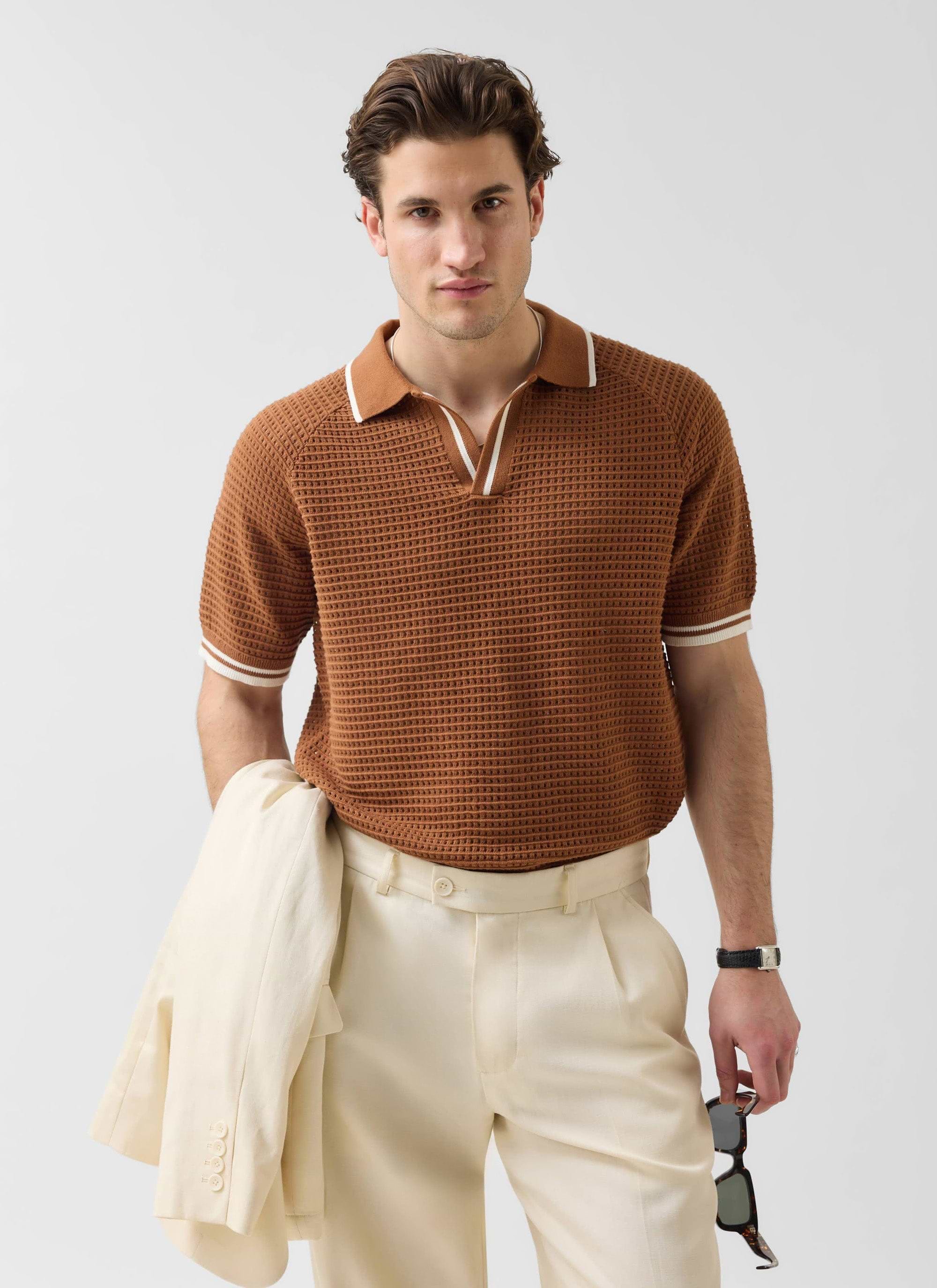 A man models the brown Percival Tennis Boxy Knitted Polo with cream trousers and a matching jacket.