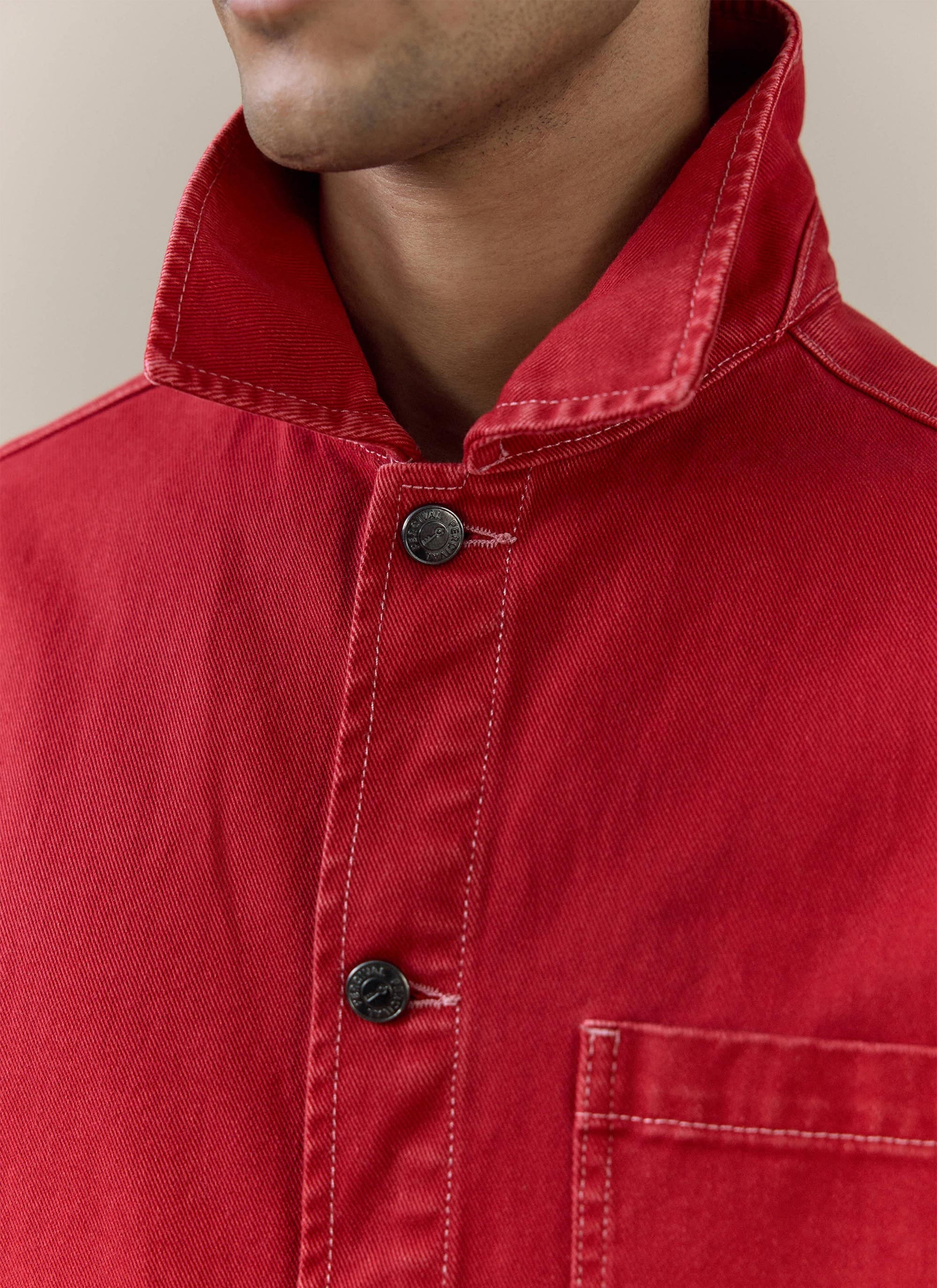 Close-up of the red cotton canvas Percival Oliver Chore Jacket, showing the vintage wash and branded button details.