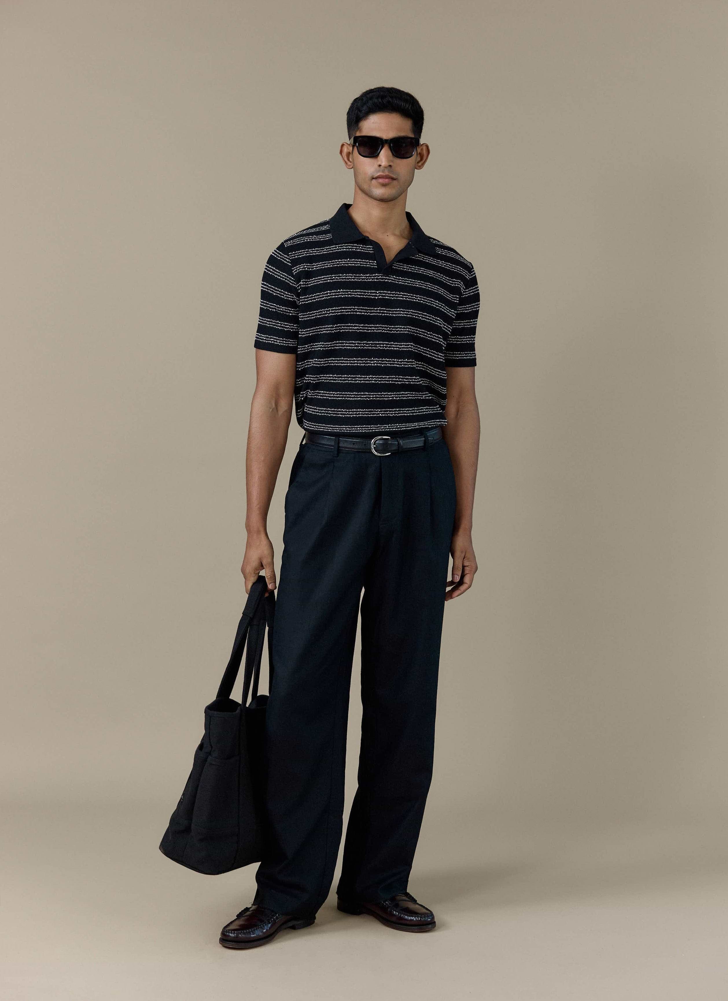 Model wearing the Percival Laurent Boxy Polo in black stripe, paired with black trousers and sunglasses.