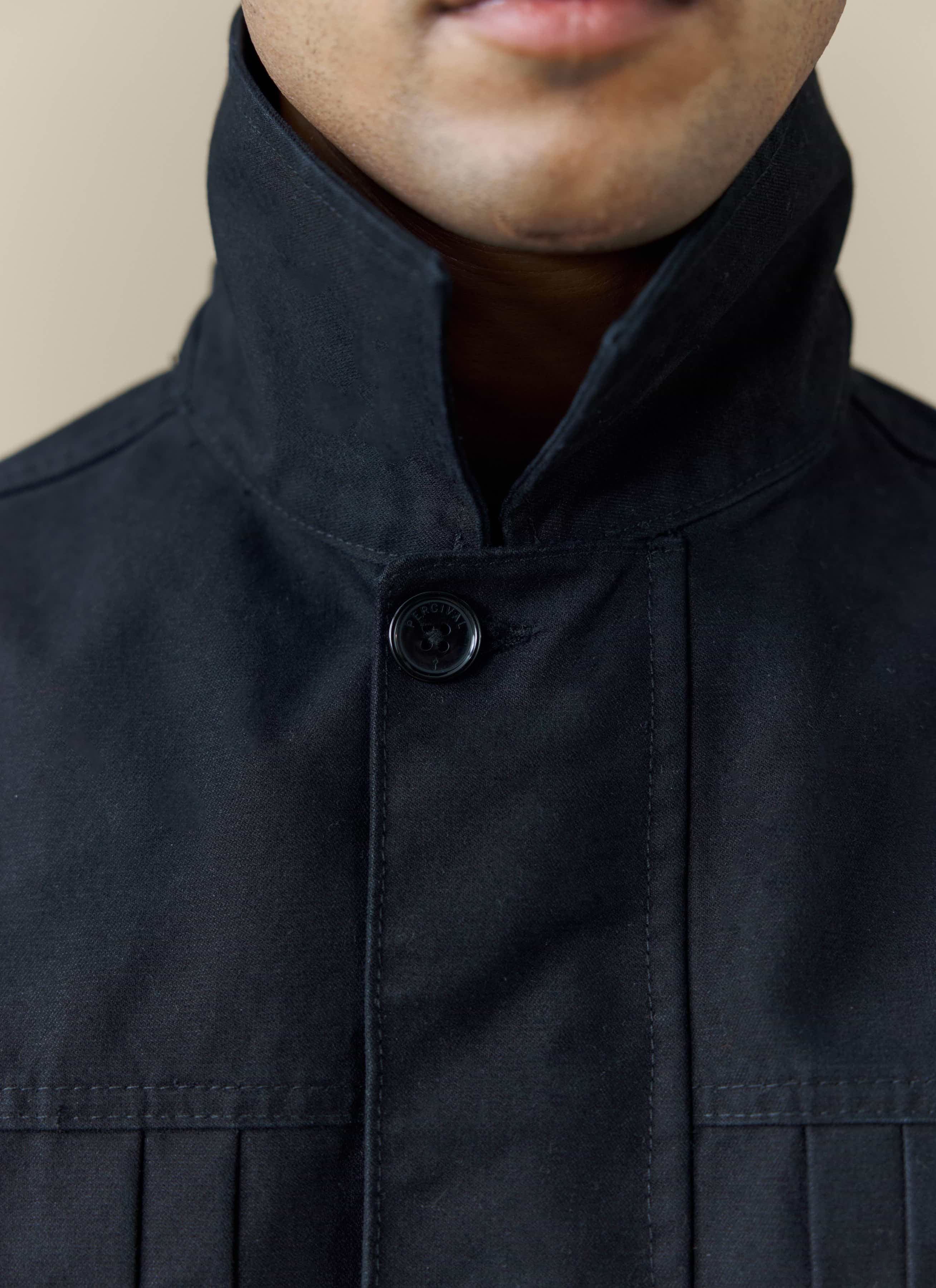 A close-up of the collar and branded button on the black cotton Ernst Jacket from Percival.