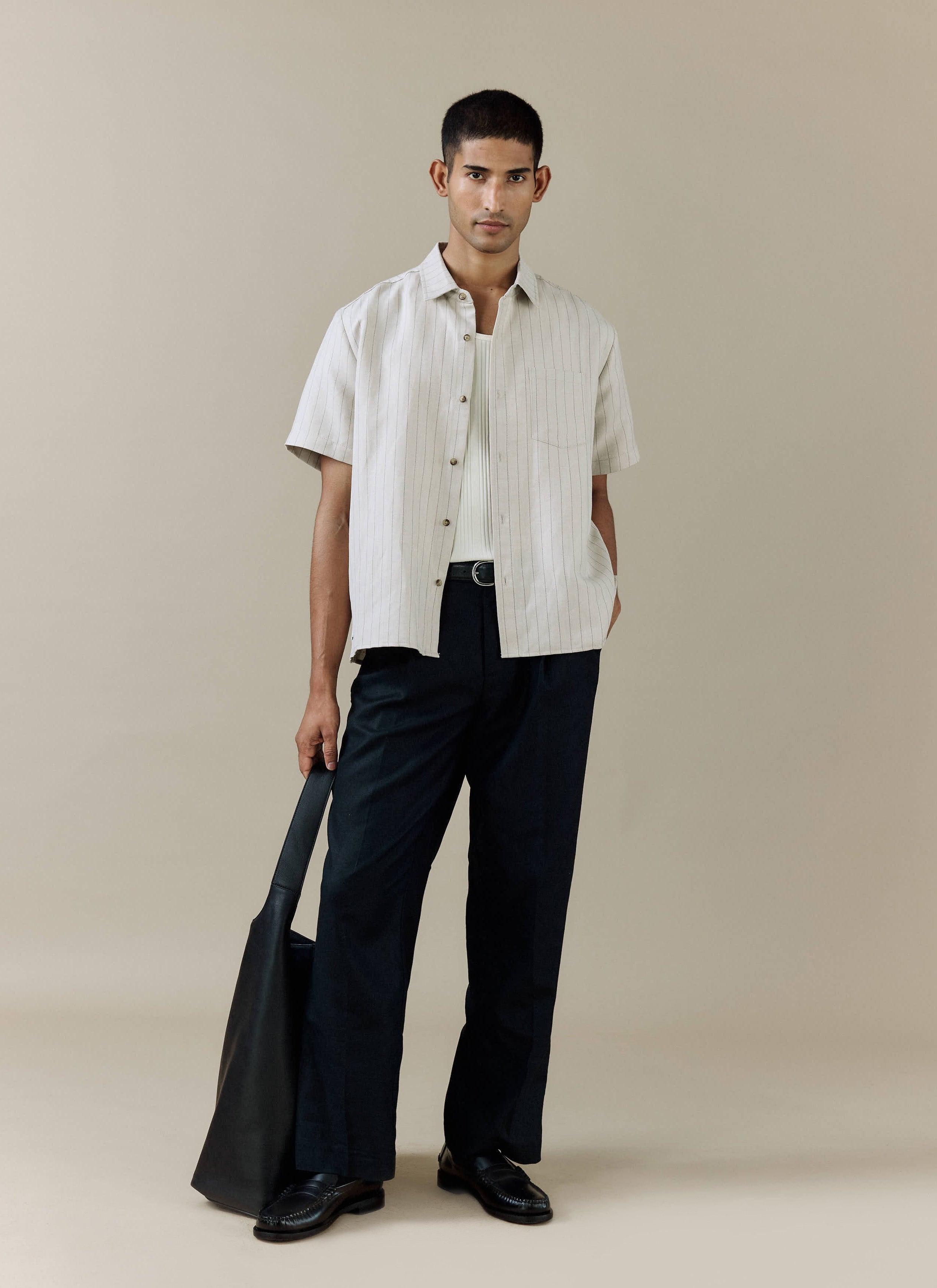 Percival cream pinstripe linen blend Striped Boxy Shirt, styled with navy trousers and a black leather tote bag.