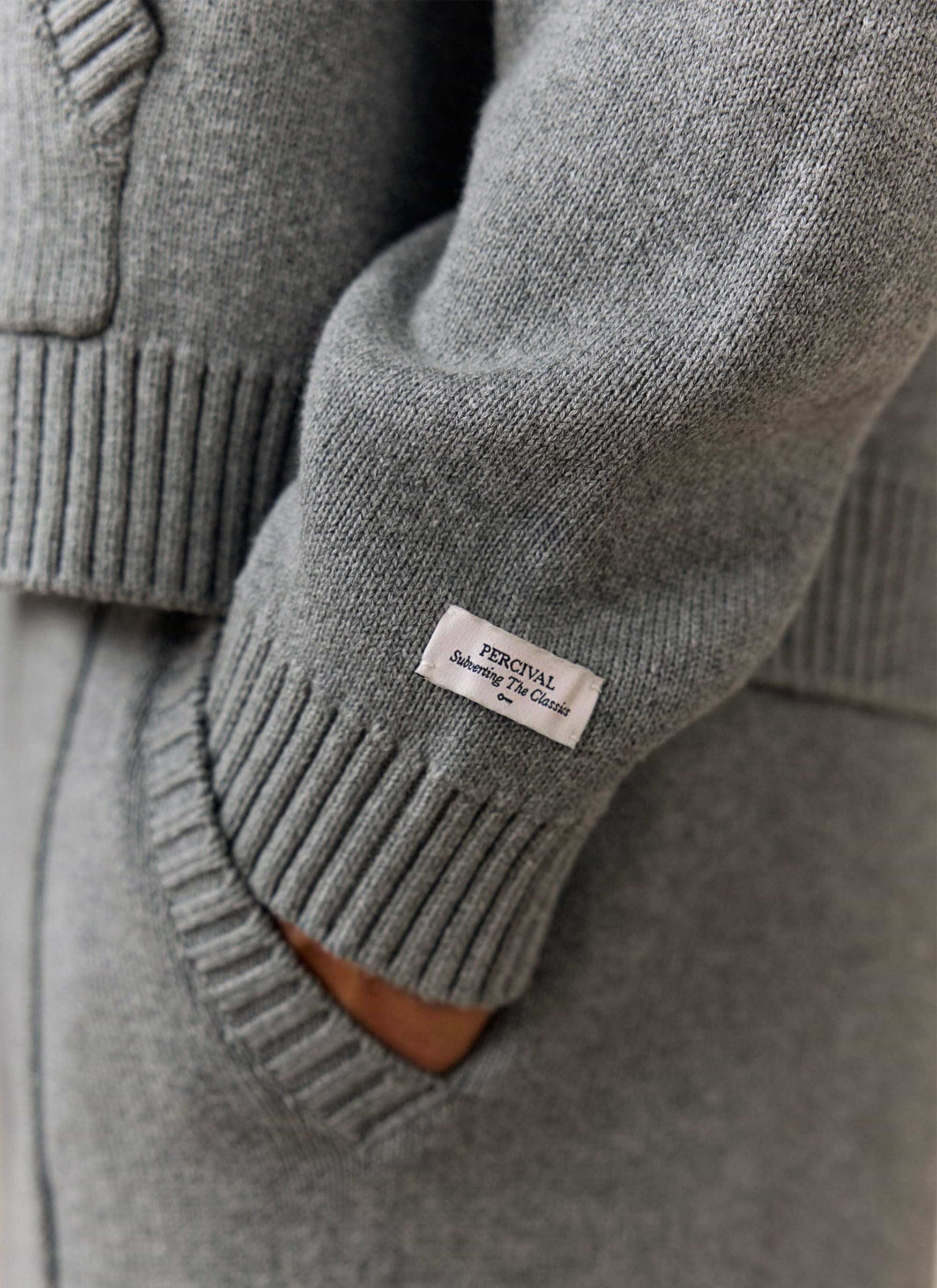 A close-up of the Percival woven brand label on the ribbed cuff of the grey cotton Chronicle Knitted Hoodie.