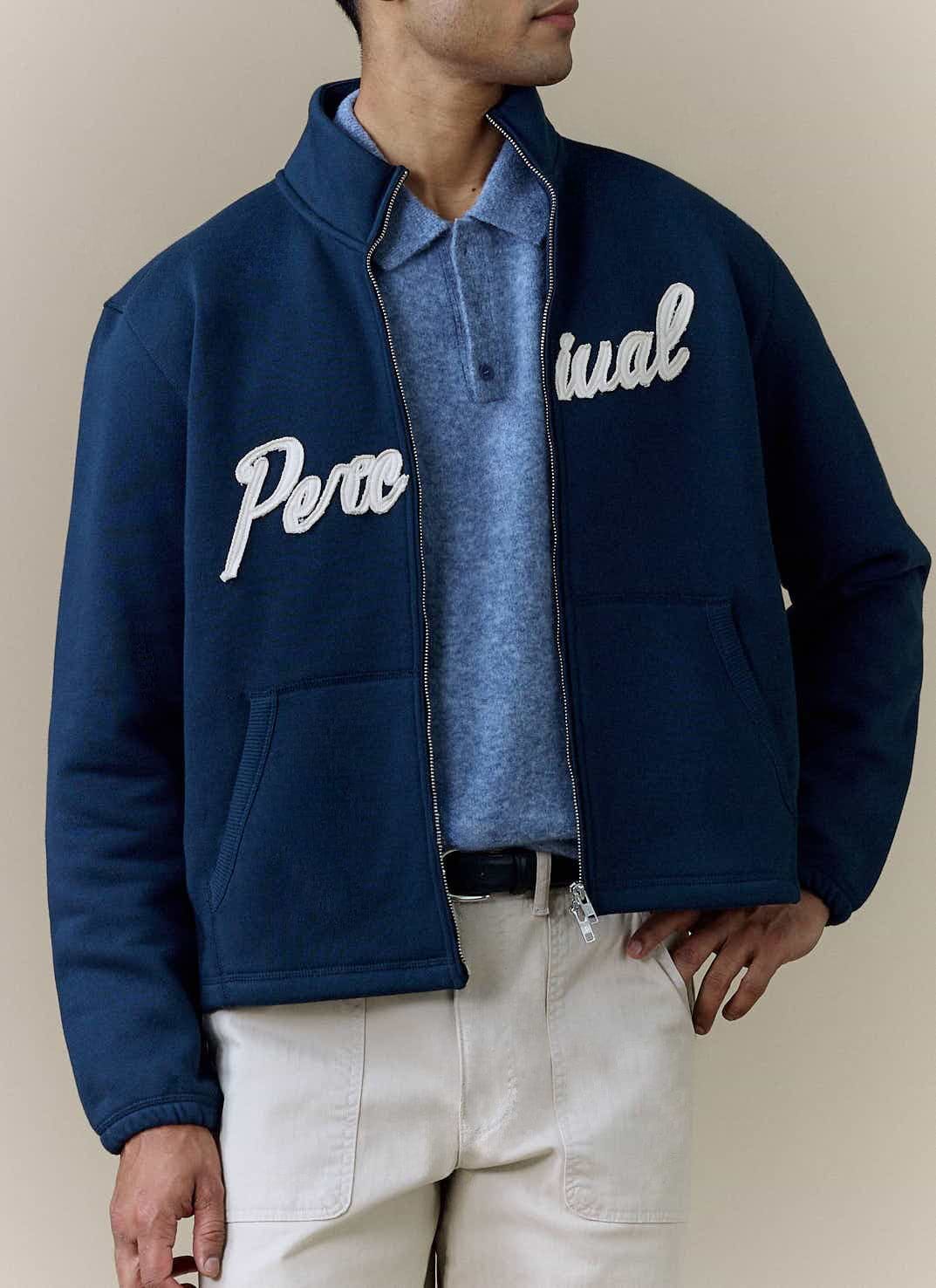 A model wears the navy Curtis Boxy Zip Funnel Neck Harrington from Percival, styled over a blue polo and light trousers.