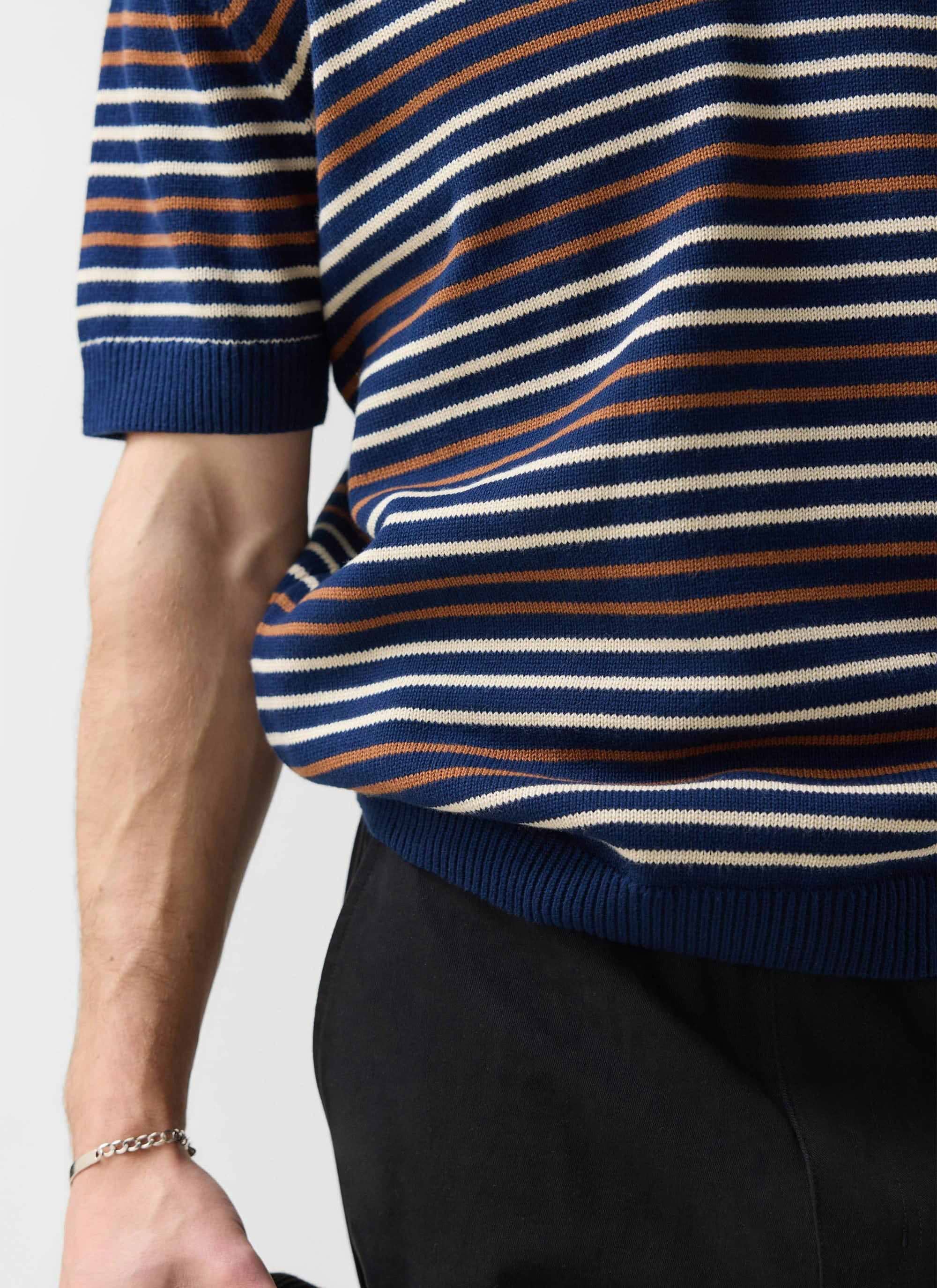 A close-up on the model wearing the Percival Douglas Boxy Knitted Polo in a navy, brown, and off-white stripe.