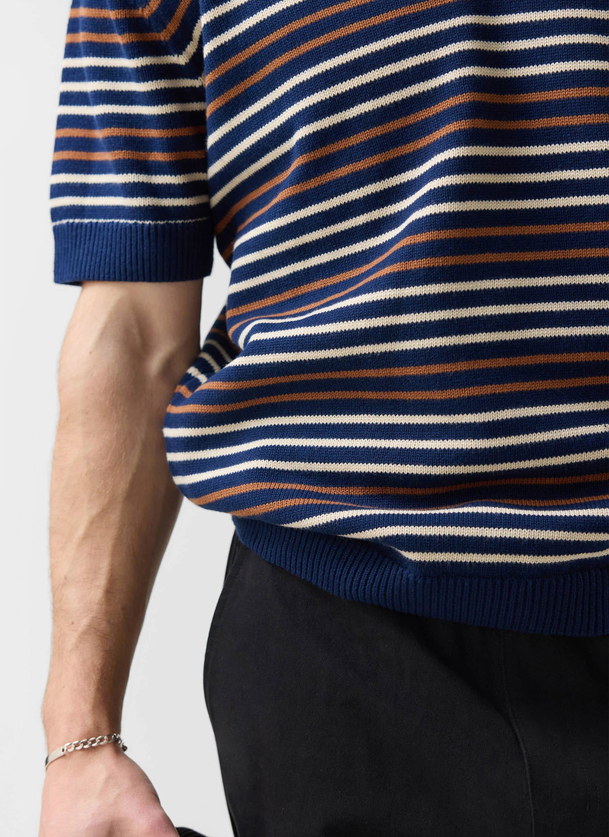 A close-up on the model wearing the Percival Douglas Boxy Knitted Polo in a navy, brown, and off-white stripe.