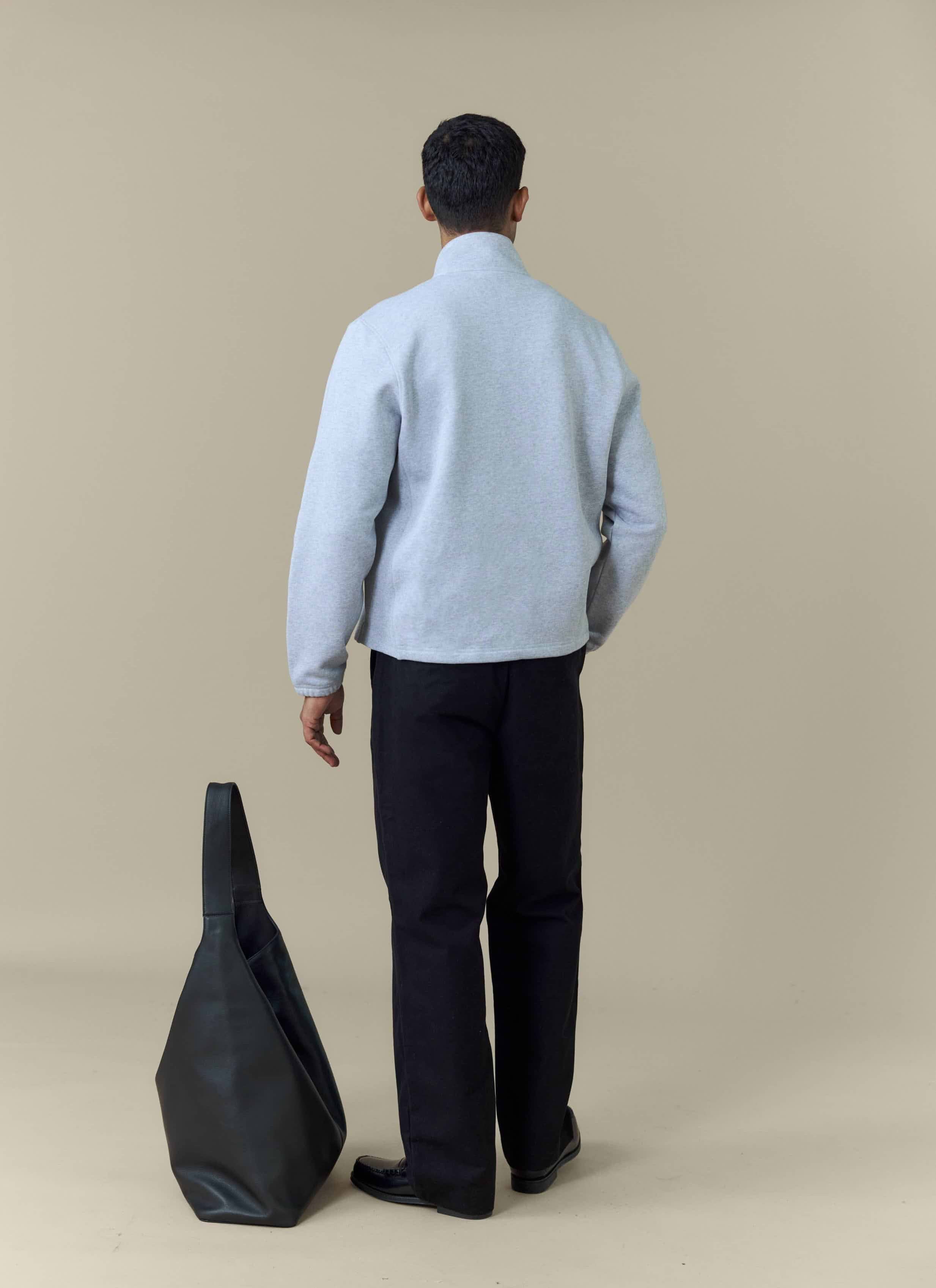 Back view of a model wearing the Percival Curtis Boxy Zip Funnel Neck Sweatshirt in Athletic Grey with black trousers.
