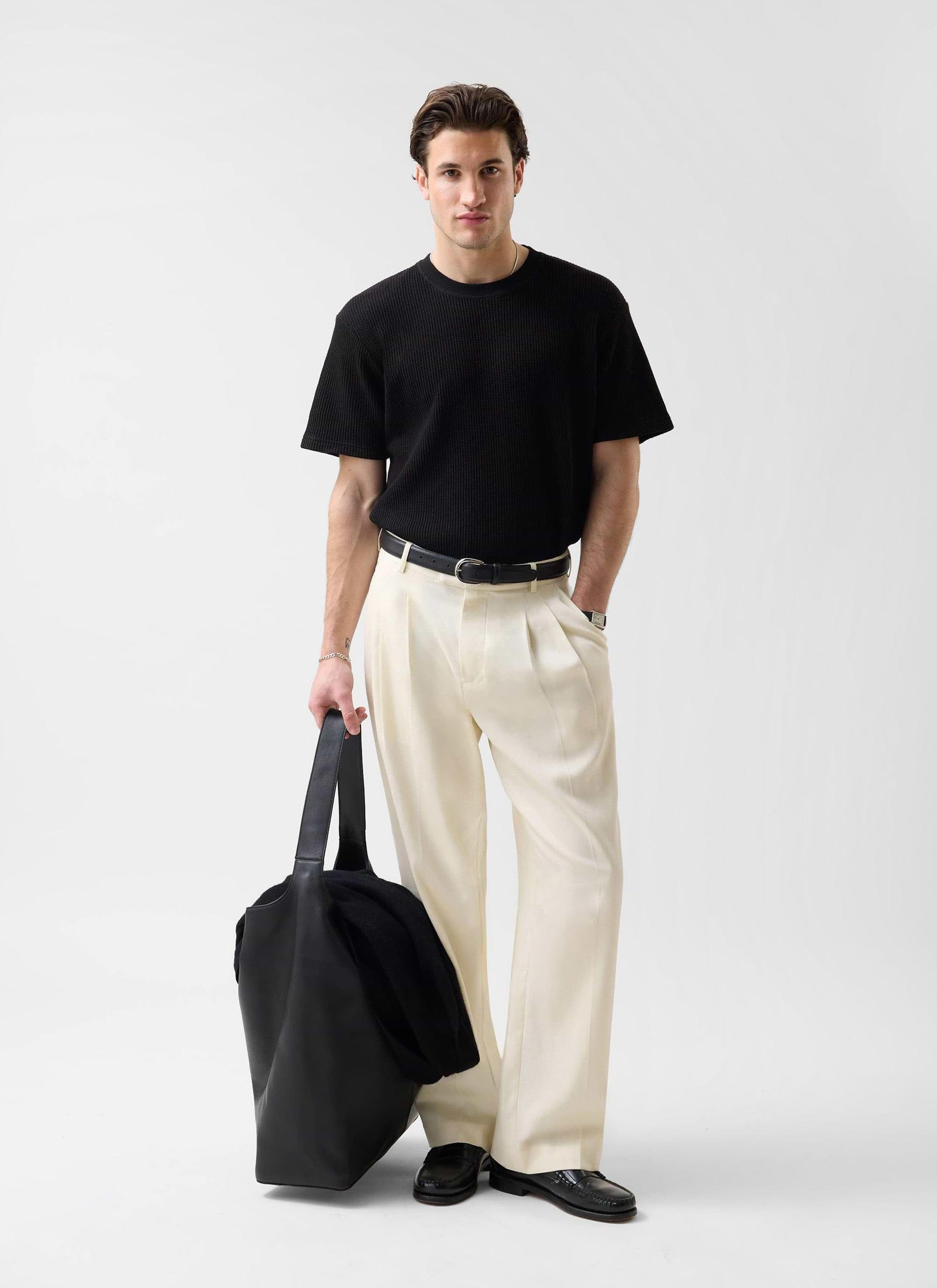 A model wears the Percival black Waffle Short Sleeve T-Shirt, styled with cream wide-leg trousers and a black tote bag.