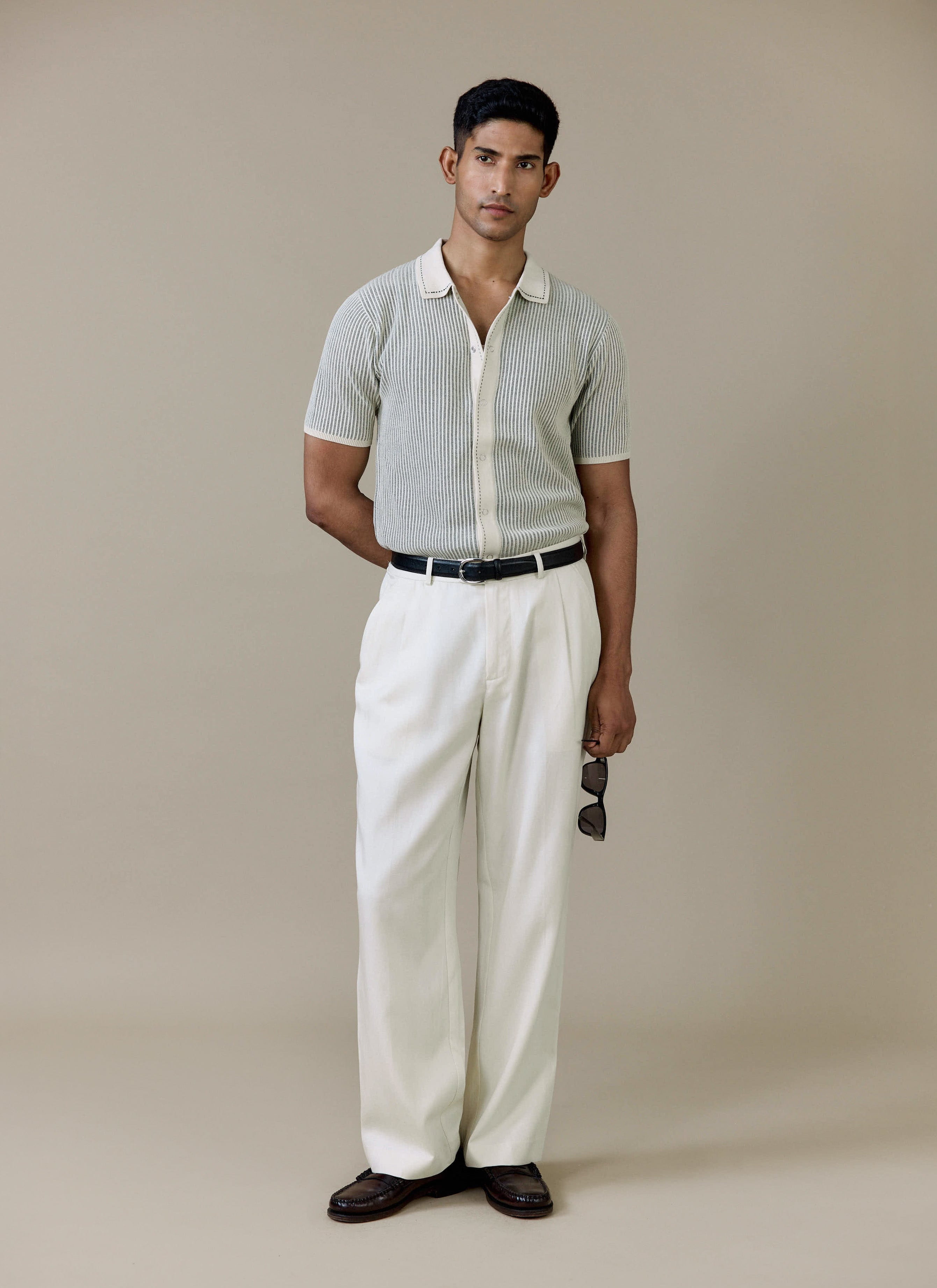 Model wearing the cream Percival Dixon Knitted Shirt with vertical stitch detail, styled with white trousers.