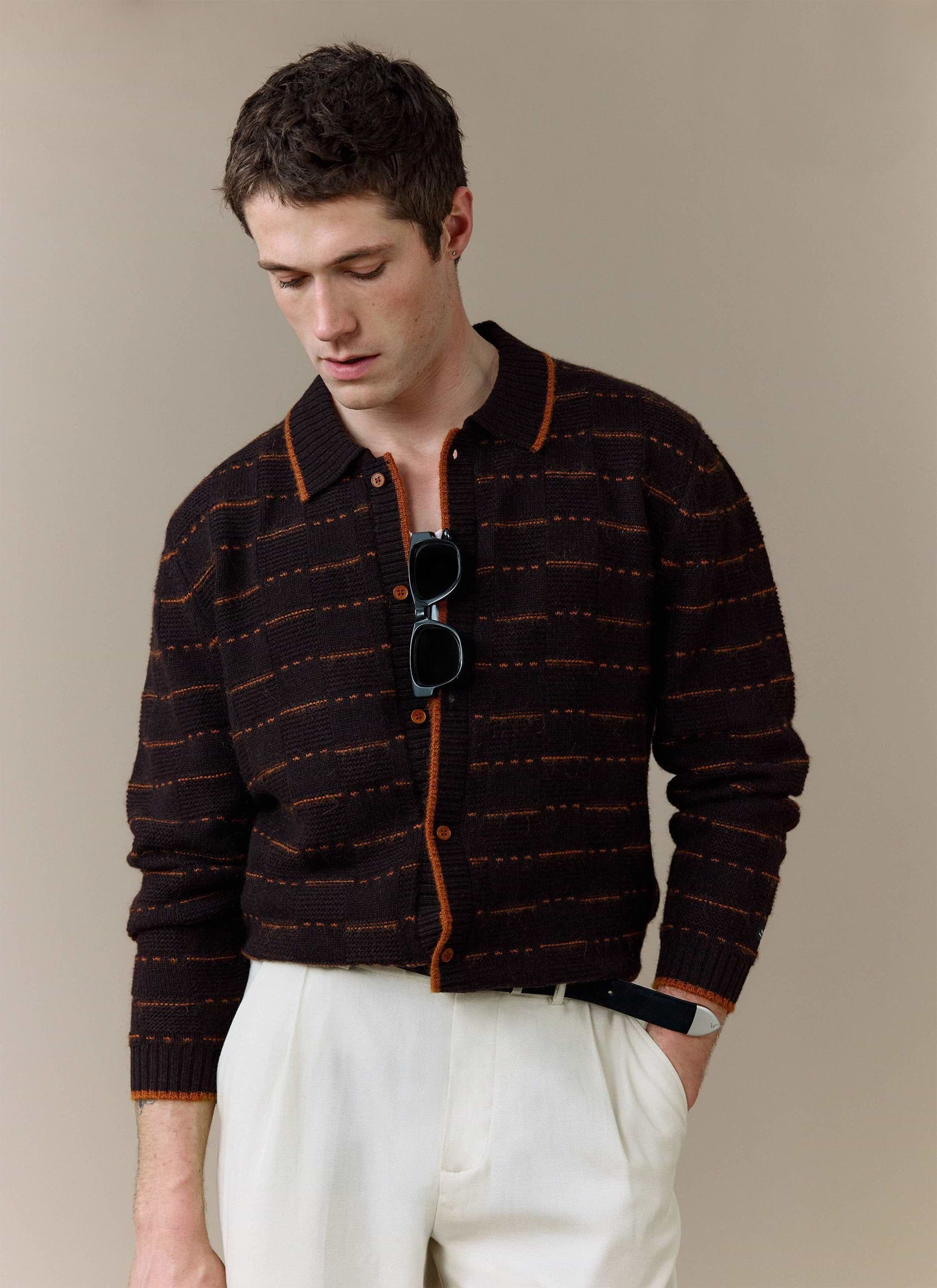 A model wears the brown Addison Long Sleeve Knitted Shirt from Percival, styled with smart white trousers.