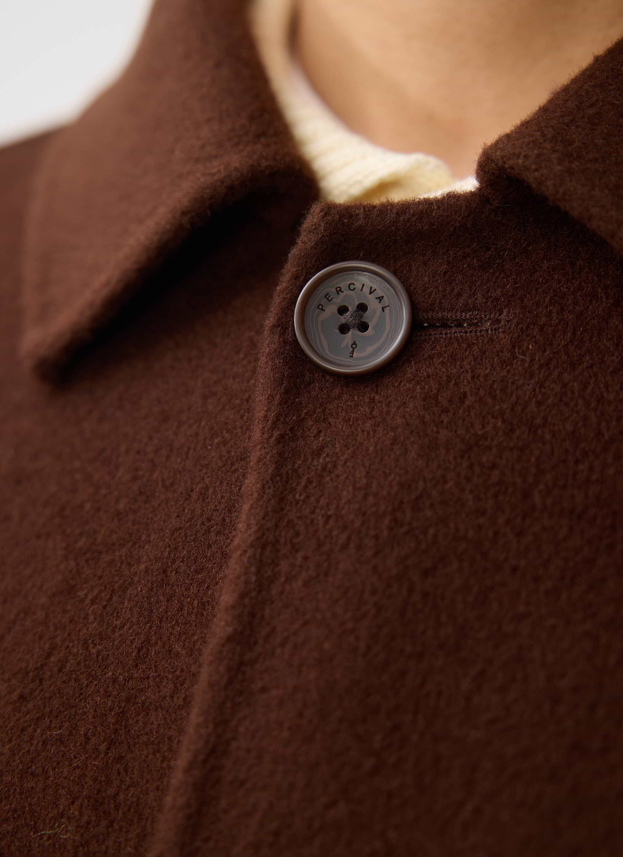 Close-up detail of the Percival Minnesota Overcoat in espresso wool, focusing on the branded button and textured fabric.