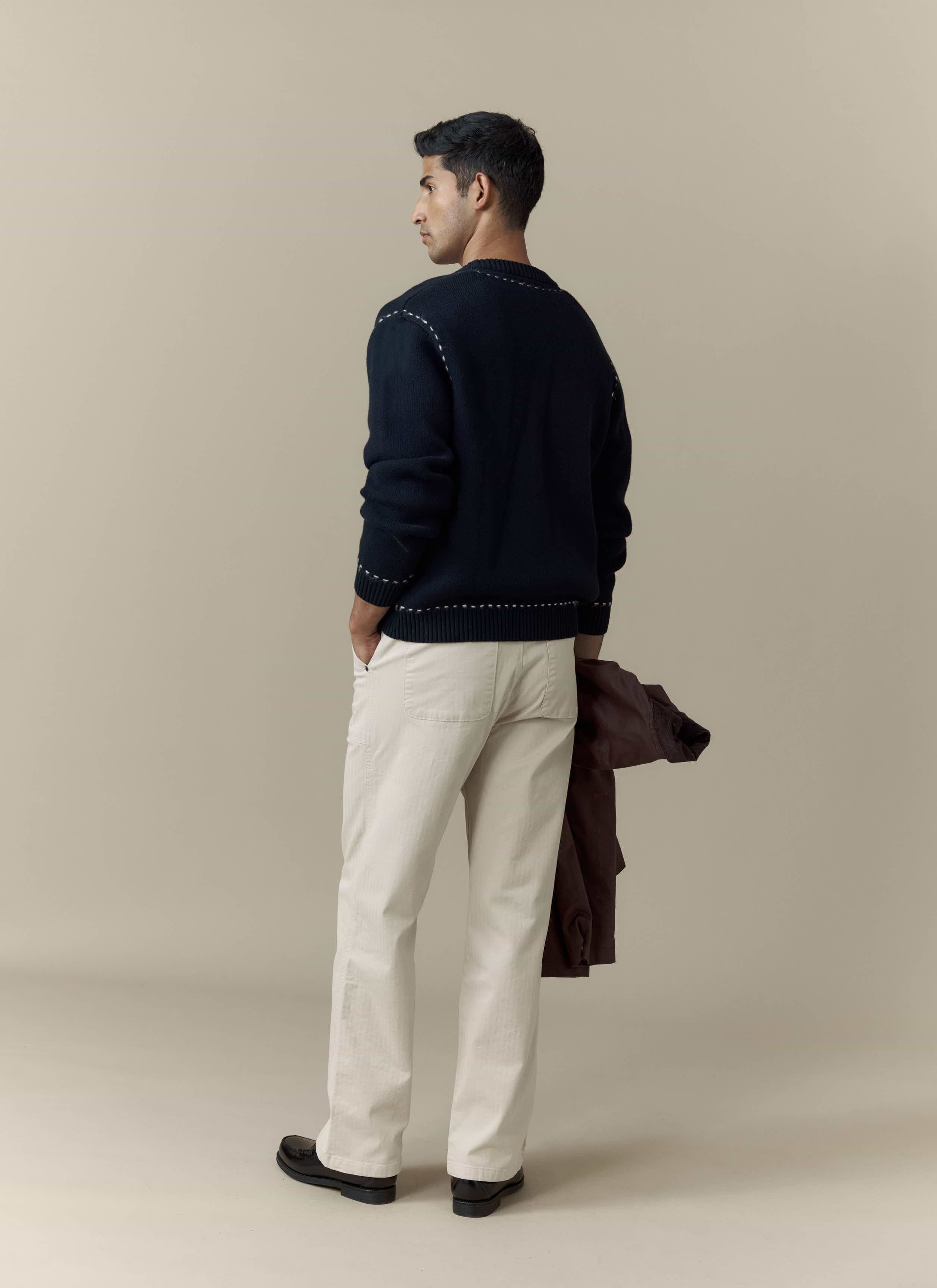 A model wears the Percival Module Boxy Cardigan in black cotton, styled with cream trousers and shot from behind.