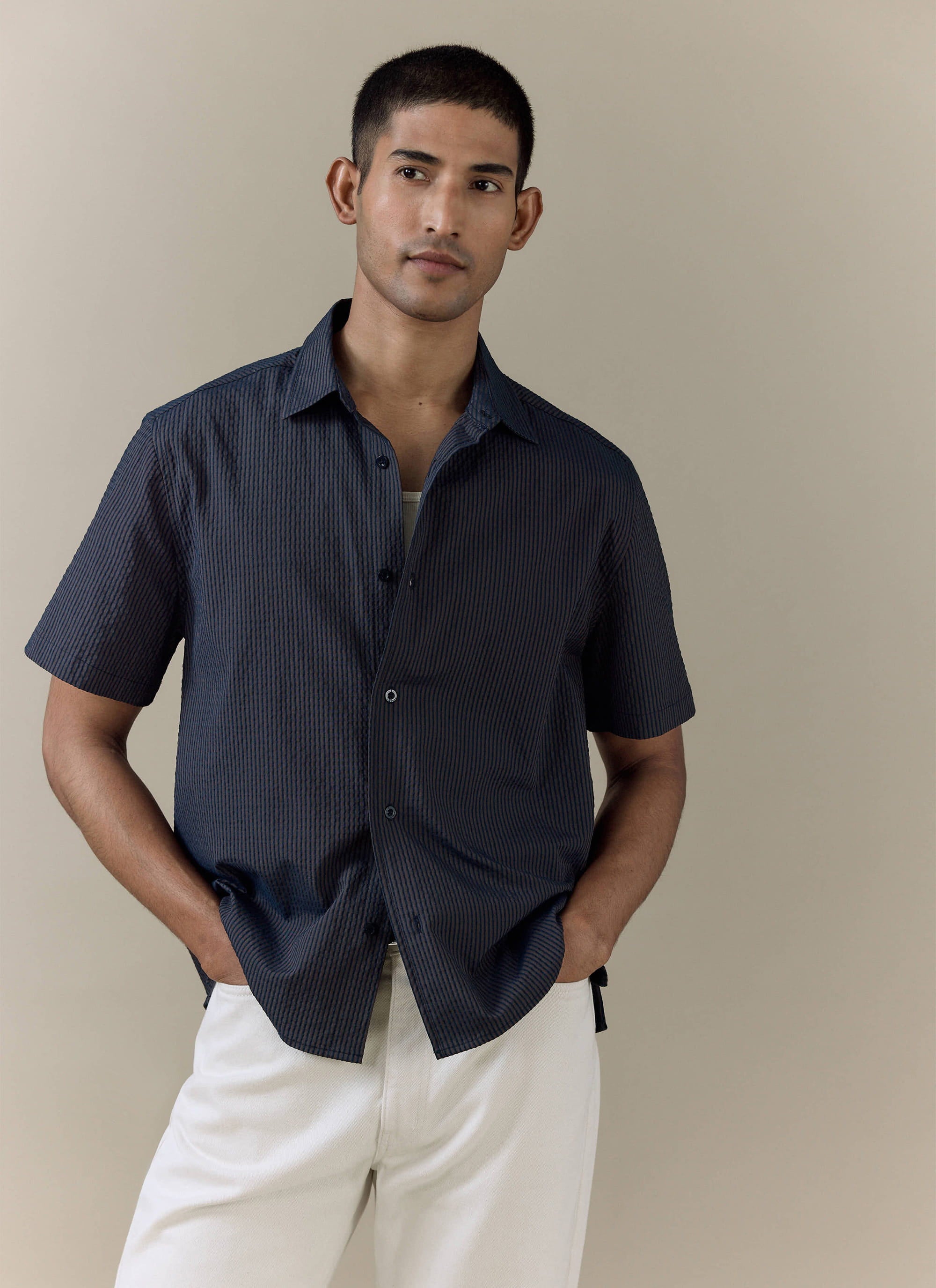 Percival Rowan Seersucker Boxy Shirt in navy stripe, featuring a textured cotton fabric and styled with white trousers.