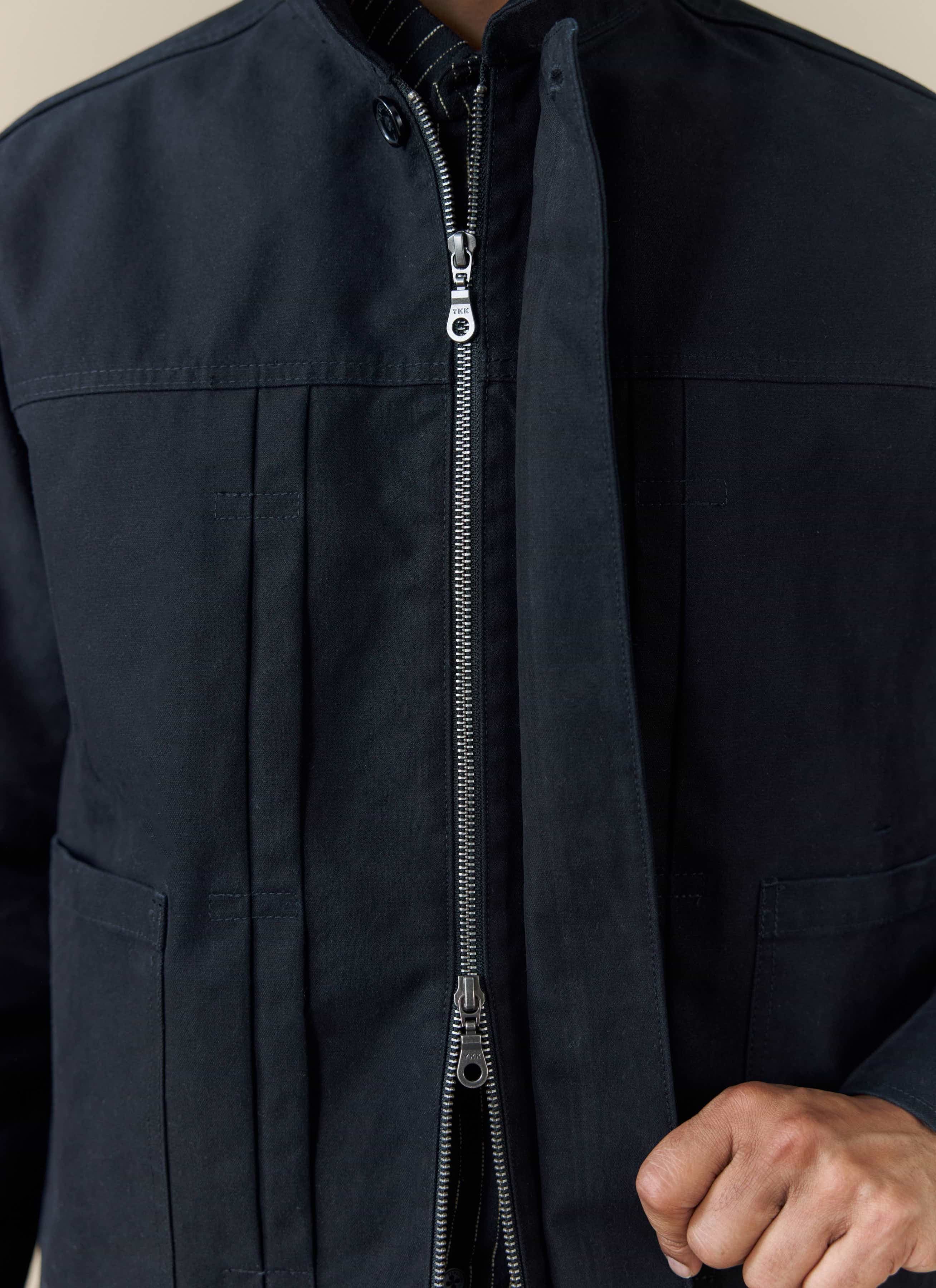 A close-up of the black Ernst Jacket from Percival, showing the double zip and pleated front detailing.