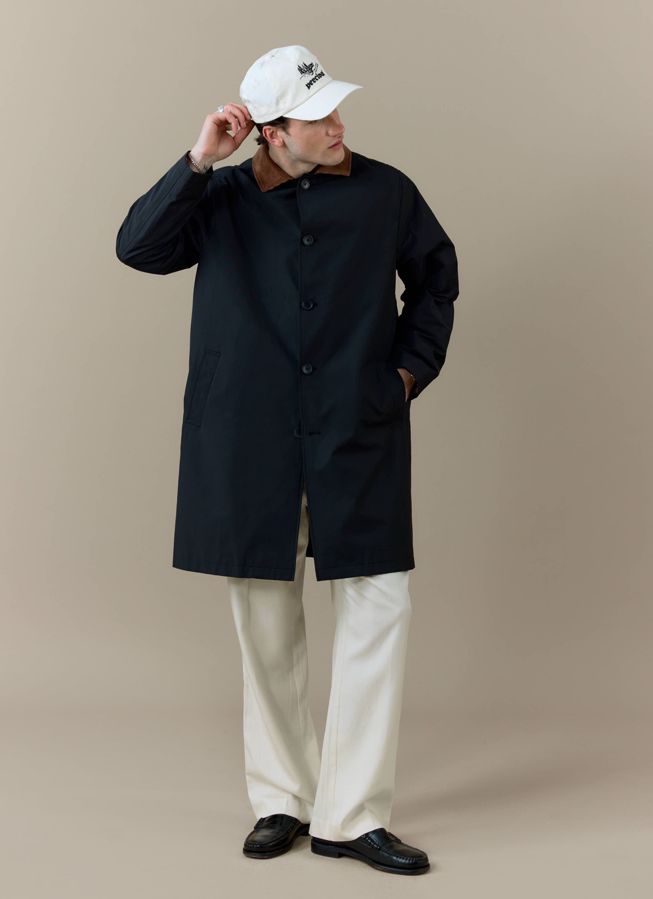 A model wearing the black Percival Cord Collar Relaxed Trench Coat with a contrast brown corduroy collar.