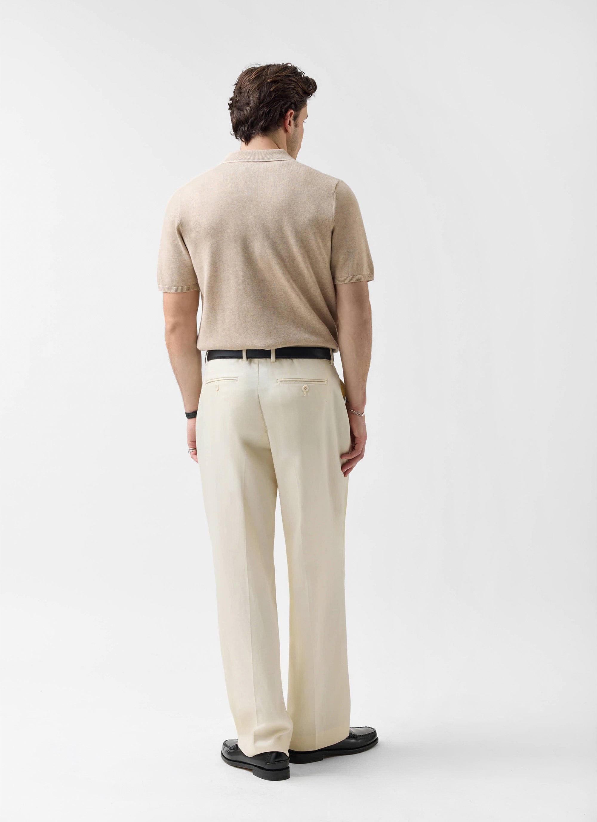 Rear view of a model wearing the Percival Contrast Trim Regular Knitted Shirt in beige with cream tailored trousers.