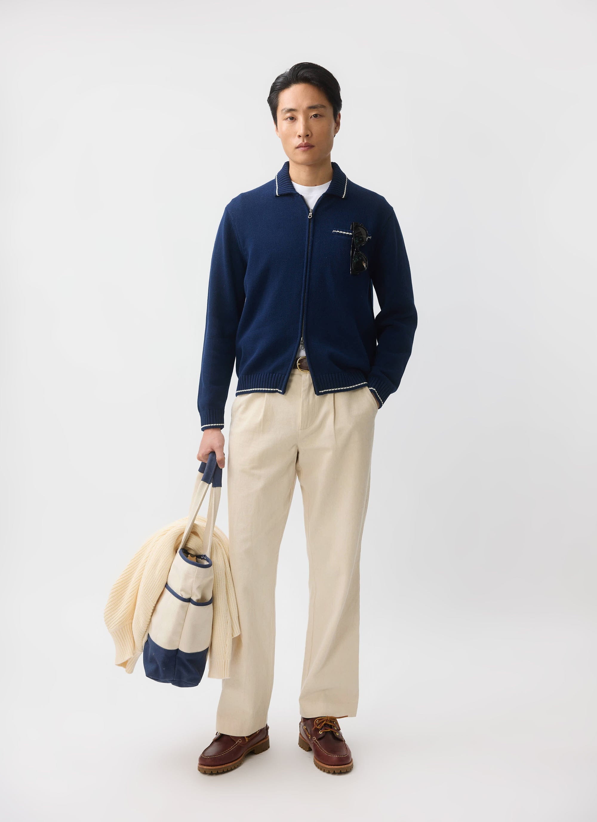 A model wears the Percival Gardner Dense Knitted Zip Cardigan in navy, styled with cream wide-leg trousers and boat shoes.