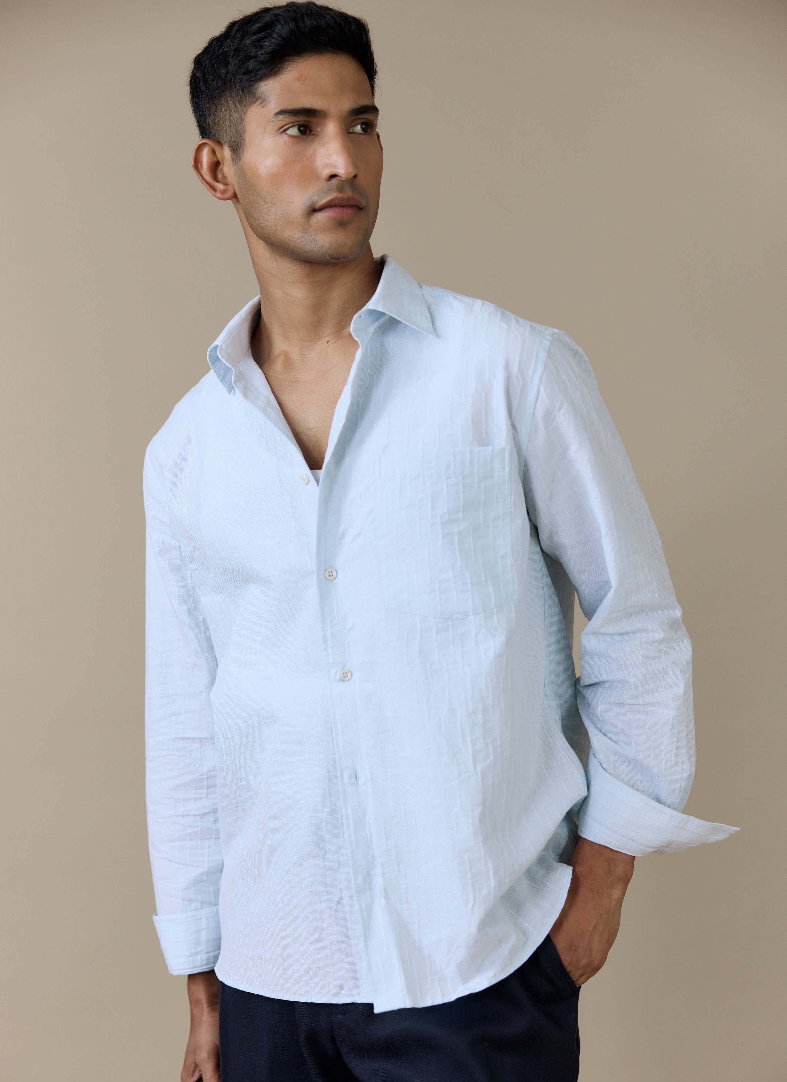 Model wears the Percival Paros Pearce Shirt in light blue, showing the textured seersucker-inspired cotton fabric.