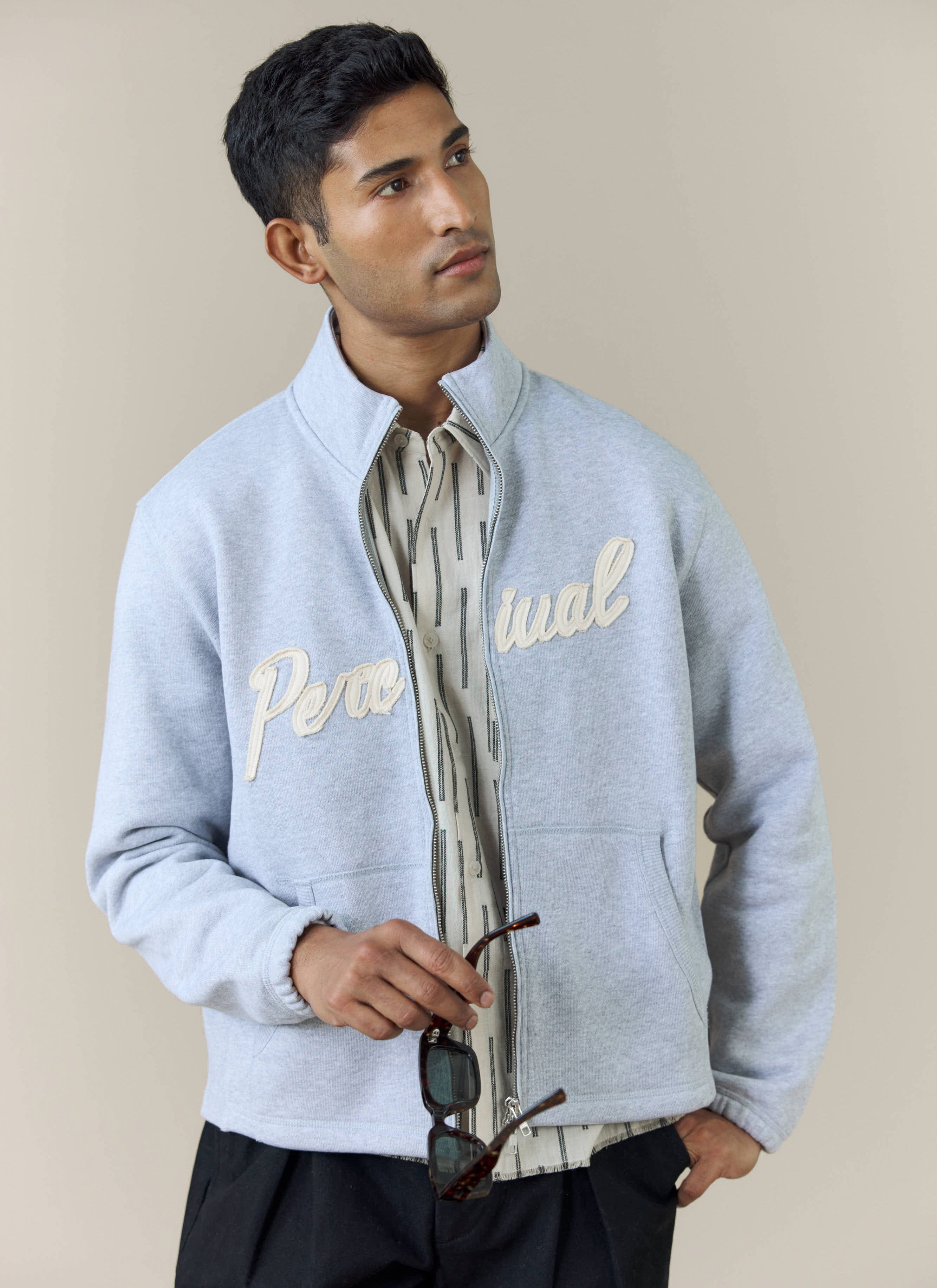 A model wears the athletic grey Curtis Boxy Zip Funnel Neck Sweatshirt by Percival, showing the textured chest logo.