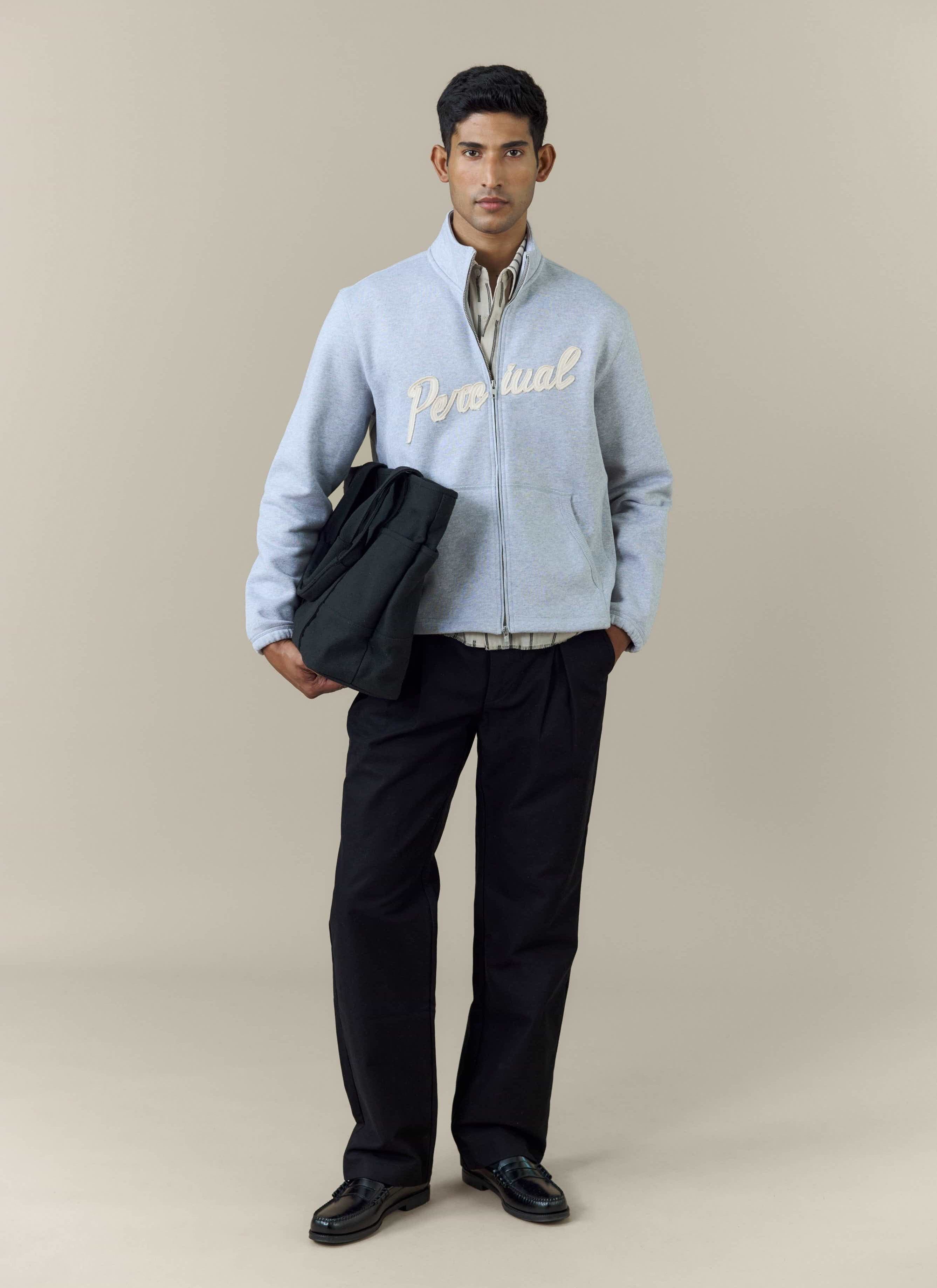 Full-length shot of a model wearing the Percival Curtis Boxy Zip Funnel Neck Sweatshirt in athletic grey with black trousers.