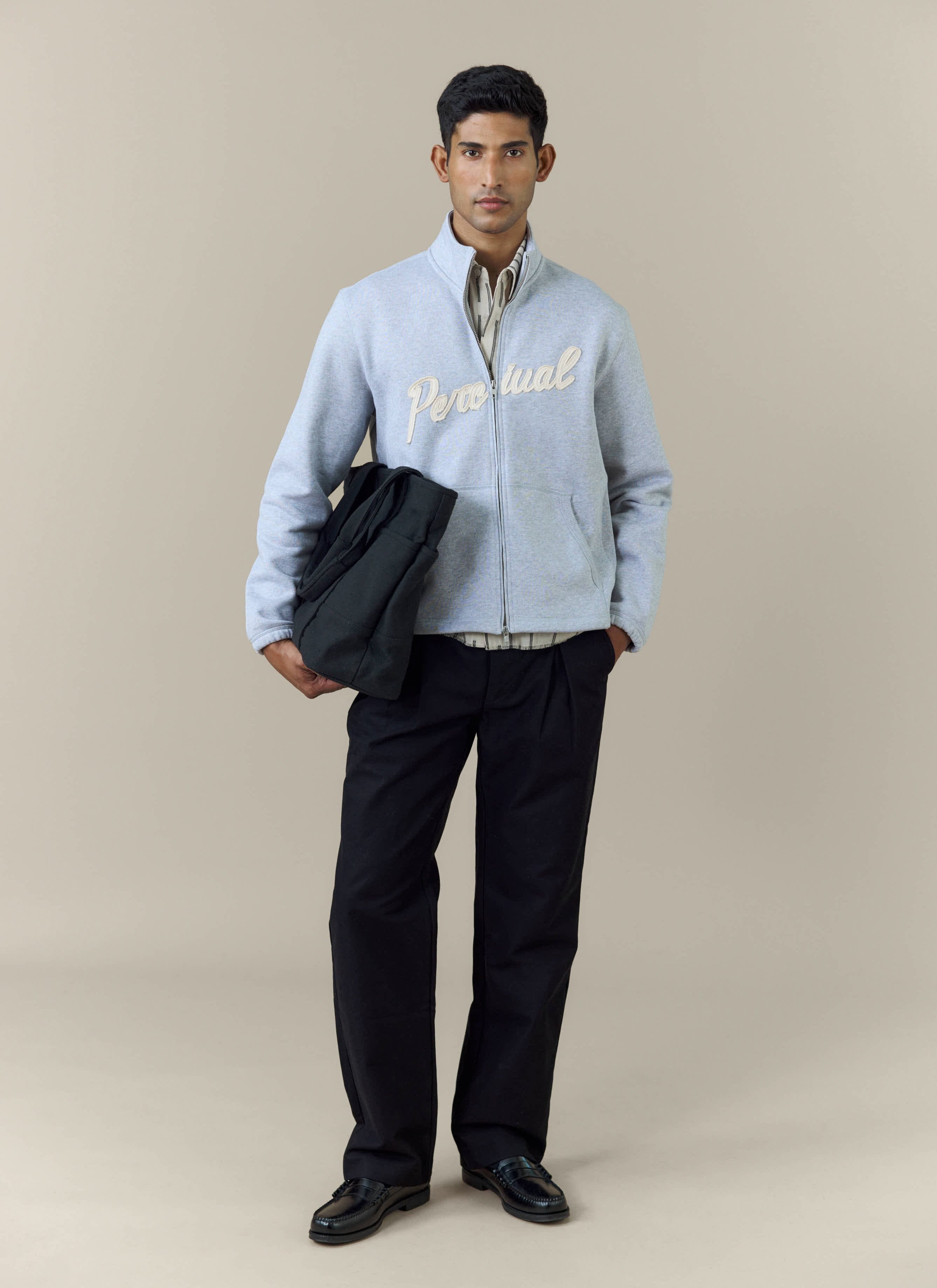 Full-length shot of a model wearing the Percival Curtis Boxy Zip Funnel Neck Sweatshirt in athletic grey with black trousers.