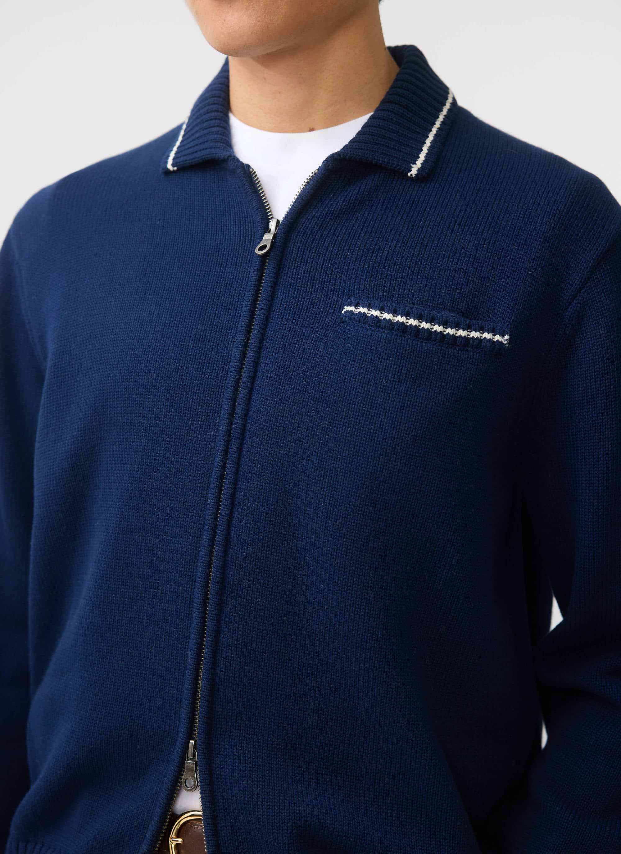 A close-up of the Percival Gardner Dense Knitted Zip Cardigan in navy, showing the contrast stitch detail on the collar.
