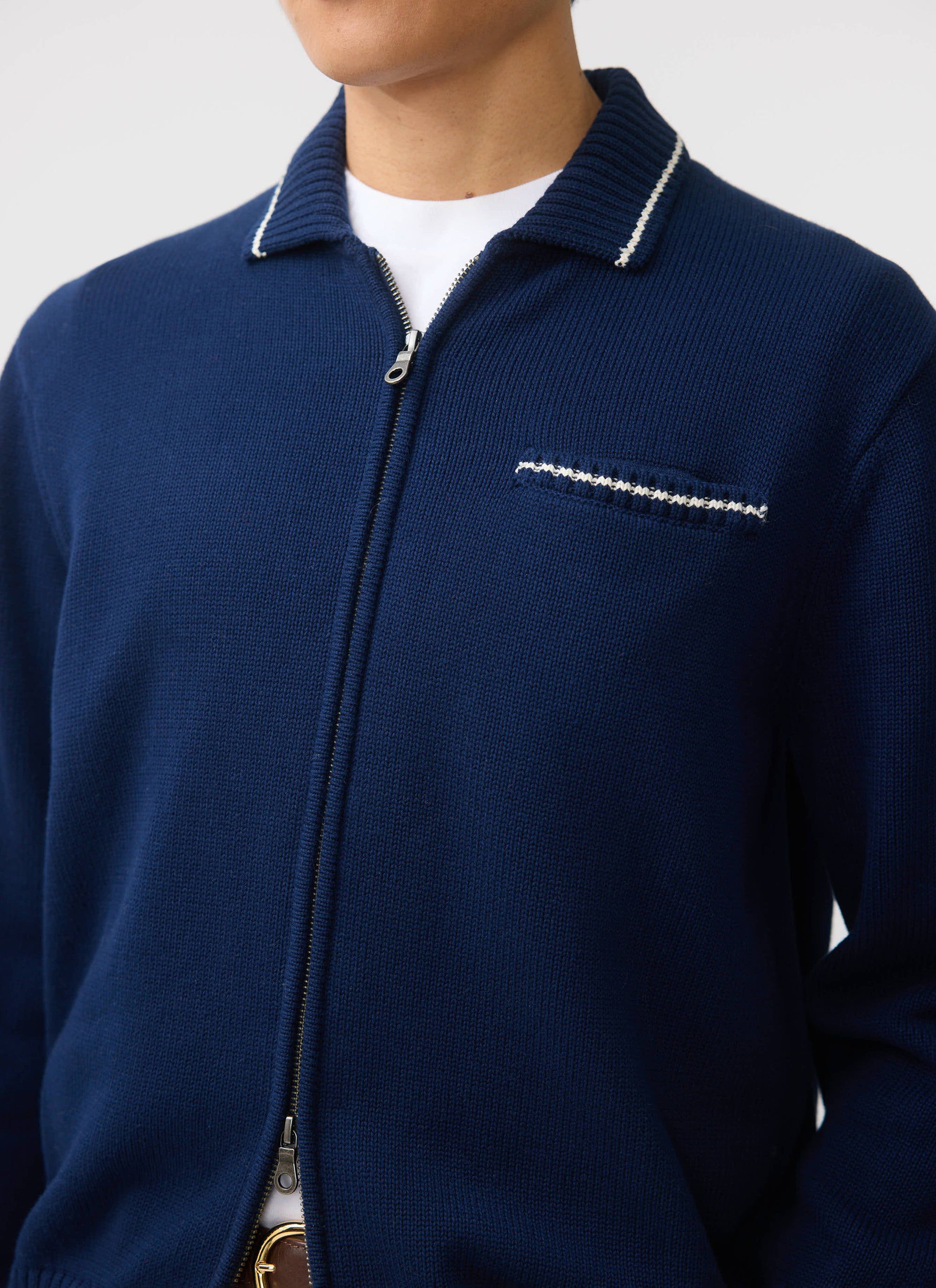 A close-up of the Percival Gardner Dense Knitted Zip Cardigan in navy, showing the contrast stitch detail on the collar.
