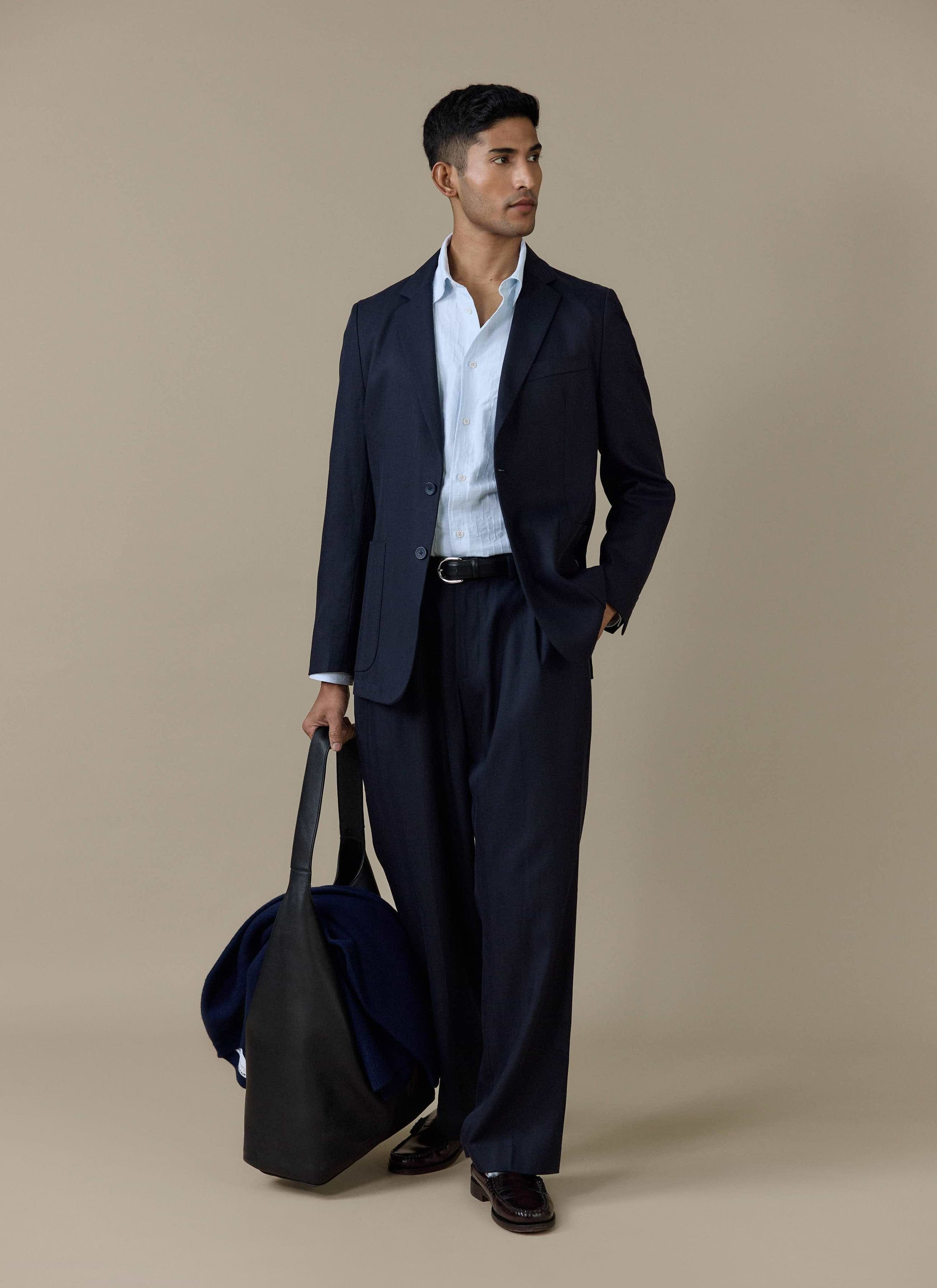 Model wears the light blue Paros Pearce Shirt by Percival styled with a navy suit and a black tote bag.