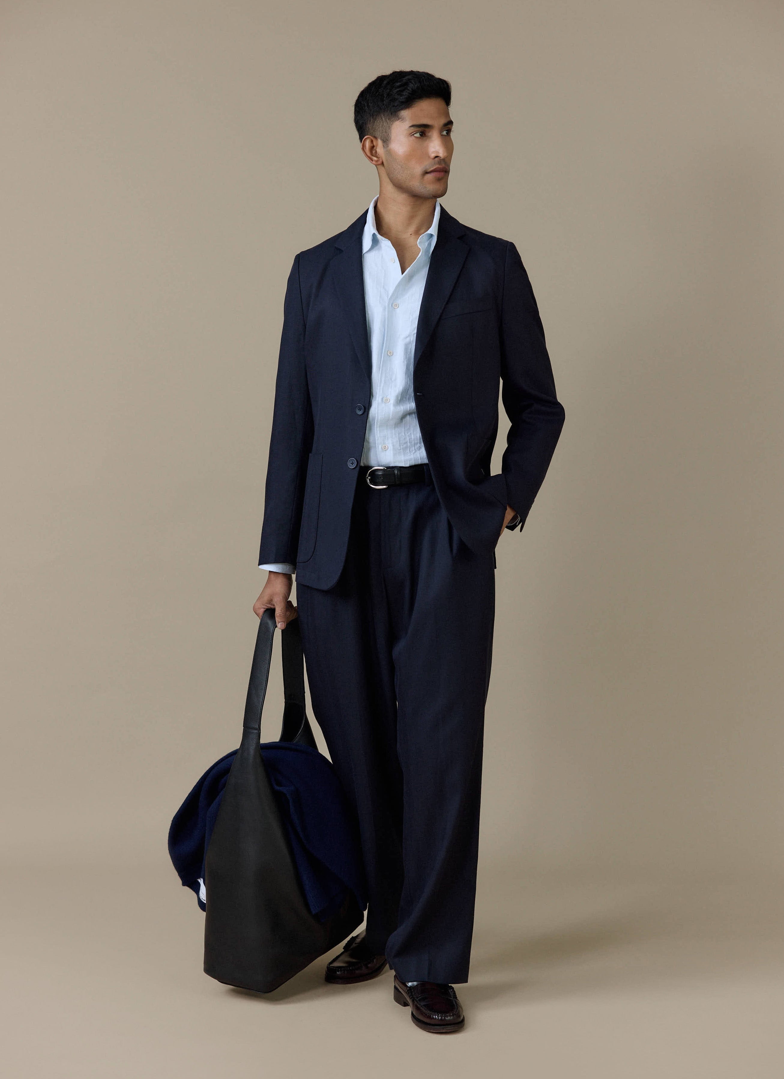 Model wears the light blue Paros Pearce Shirt by Percival styled with a navy suit and a black tote bag.