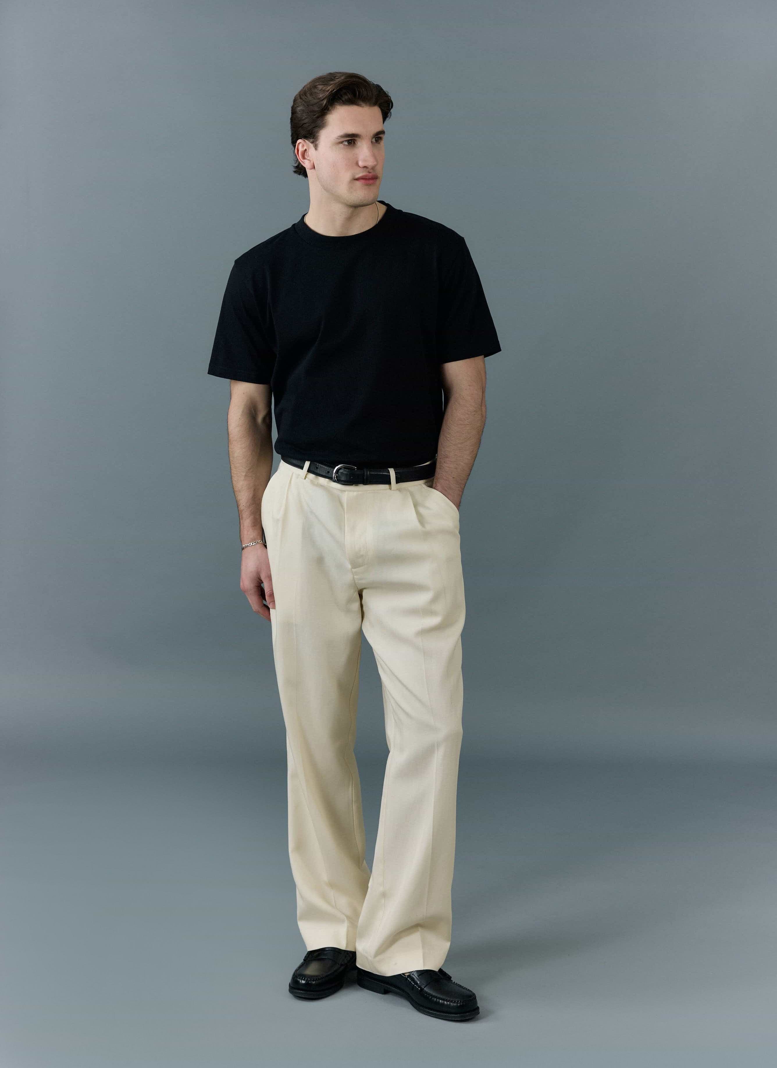 Model wears the Percival black regular fit organic cotton t-shirt with cream trousers and black loafers.