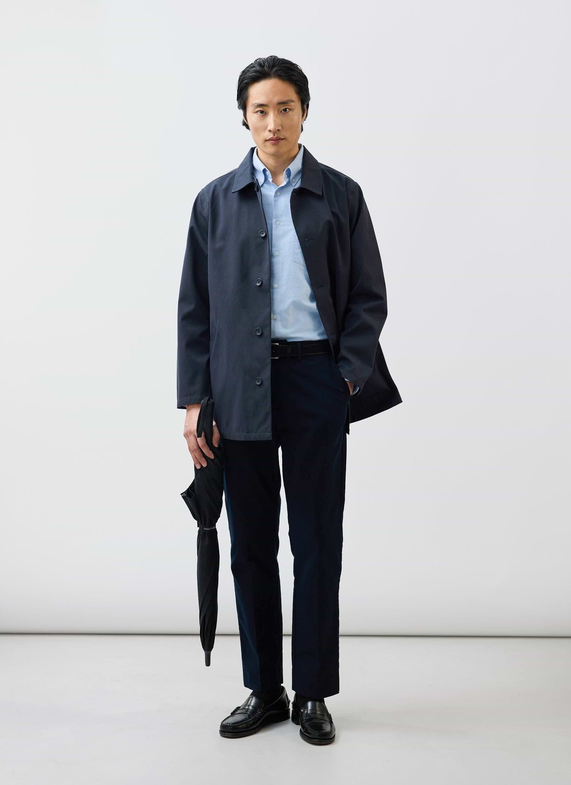 A model wearing the Percival Sherlock Short Trench Coat in midnight navy, featuring waterproof technical fabric.