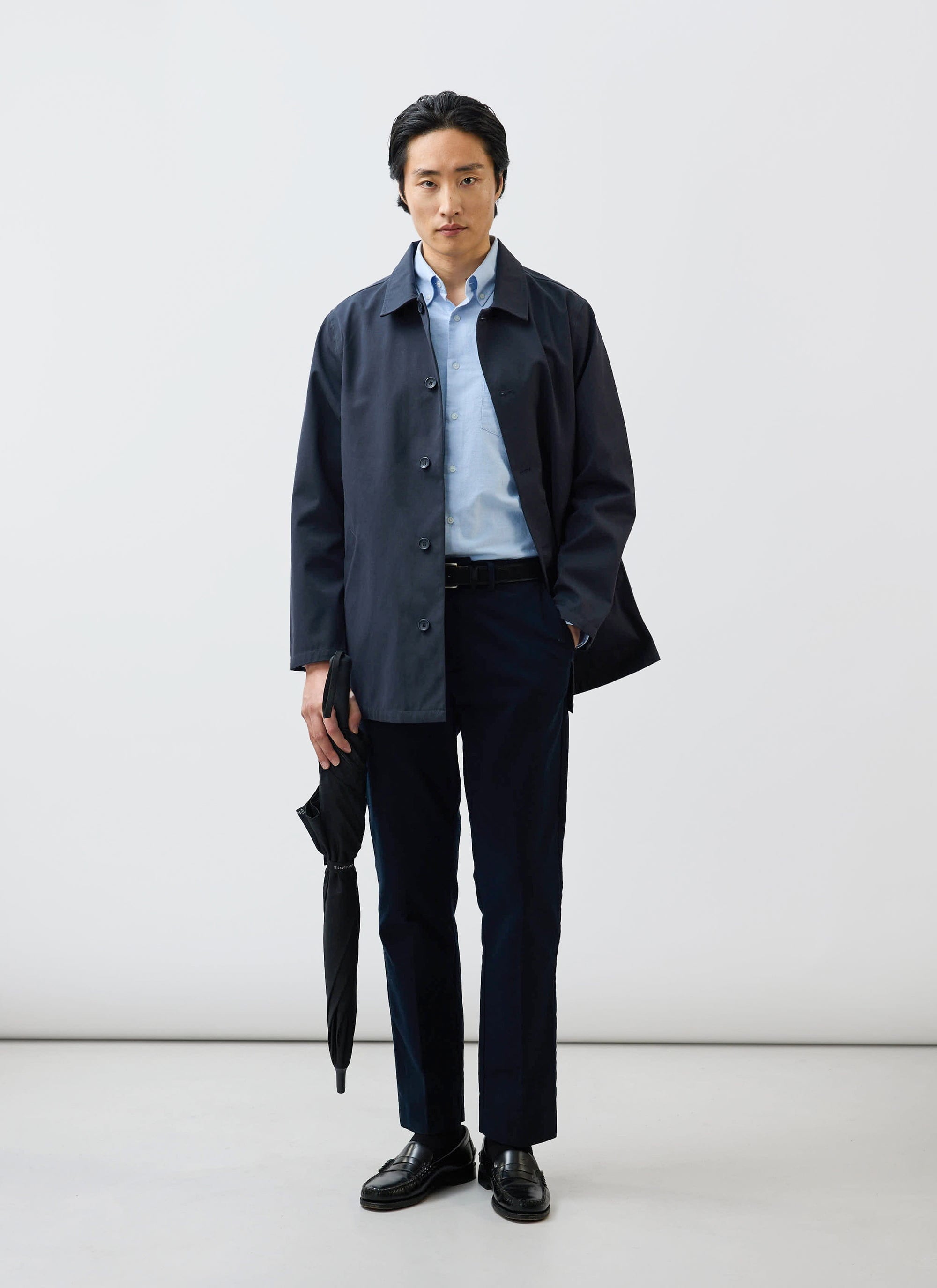 A model wearing the Percival Sherlock Short Trench Coat in midnight navy, featuring waterproof technical fabric.