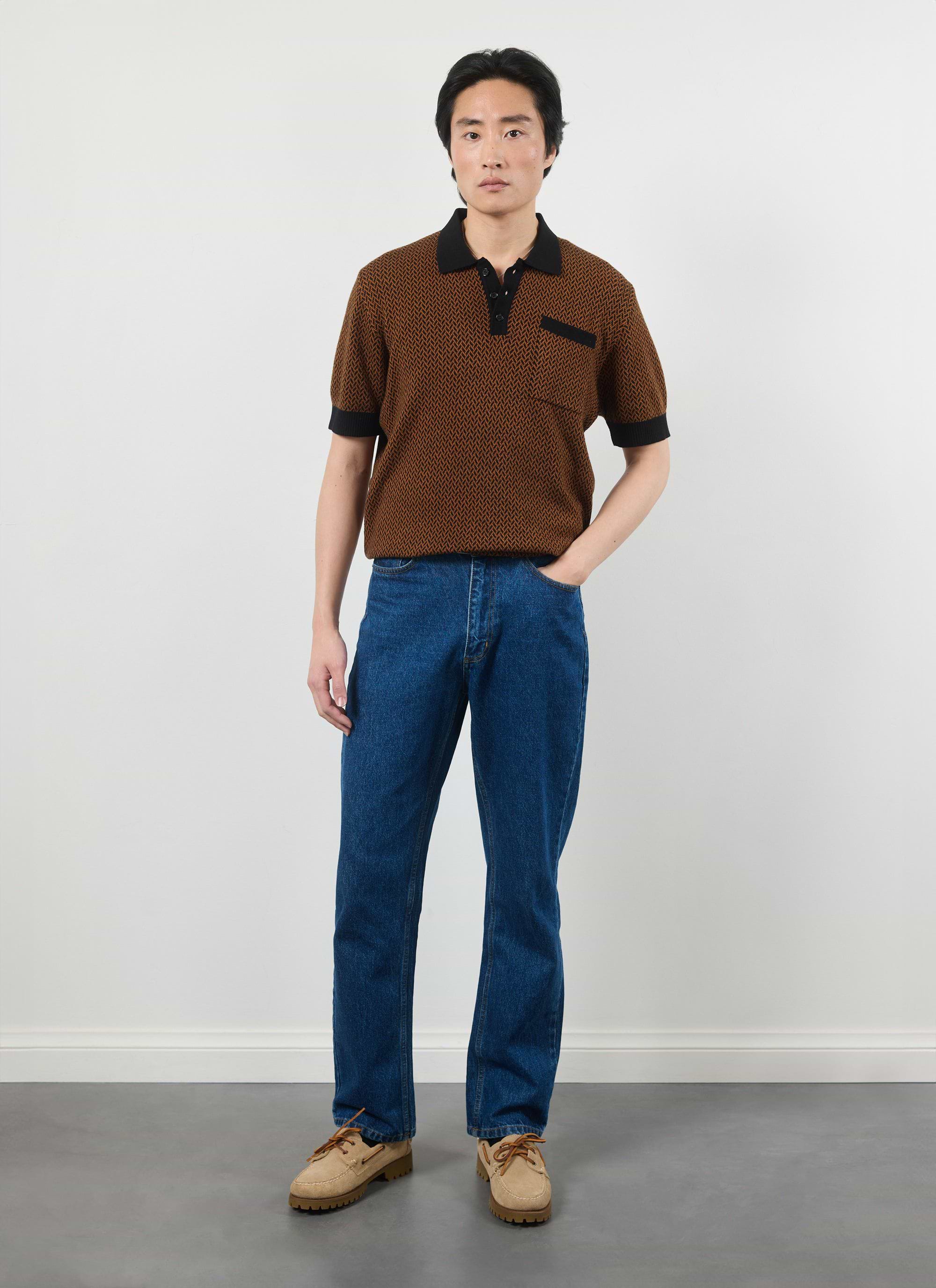A model wears the Percival Casa Martini Knitted Polo in Espresso, styled with blue jeans and tan suede shoes.