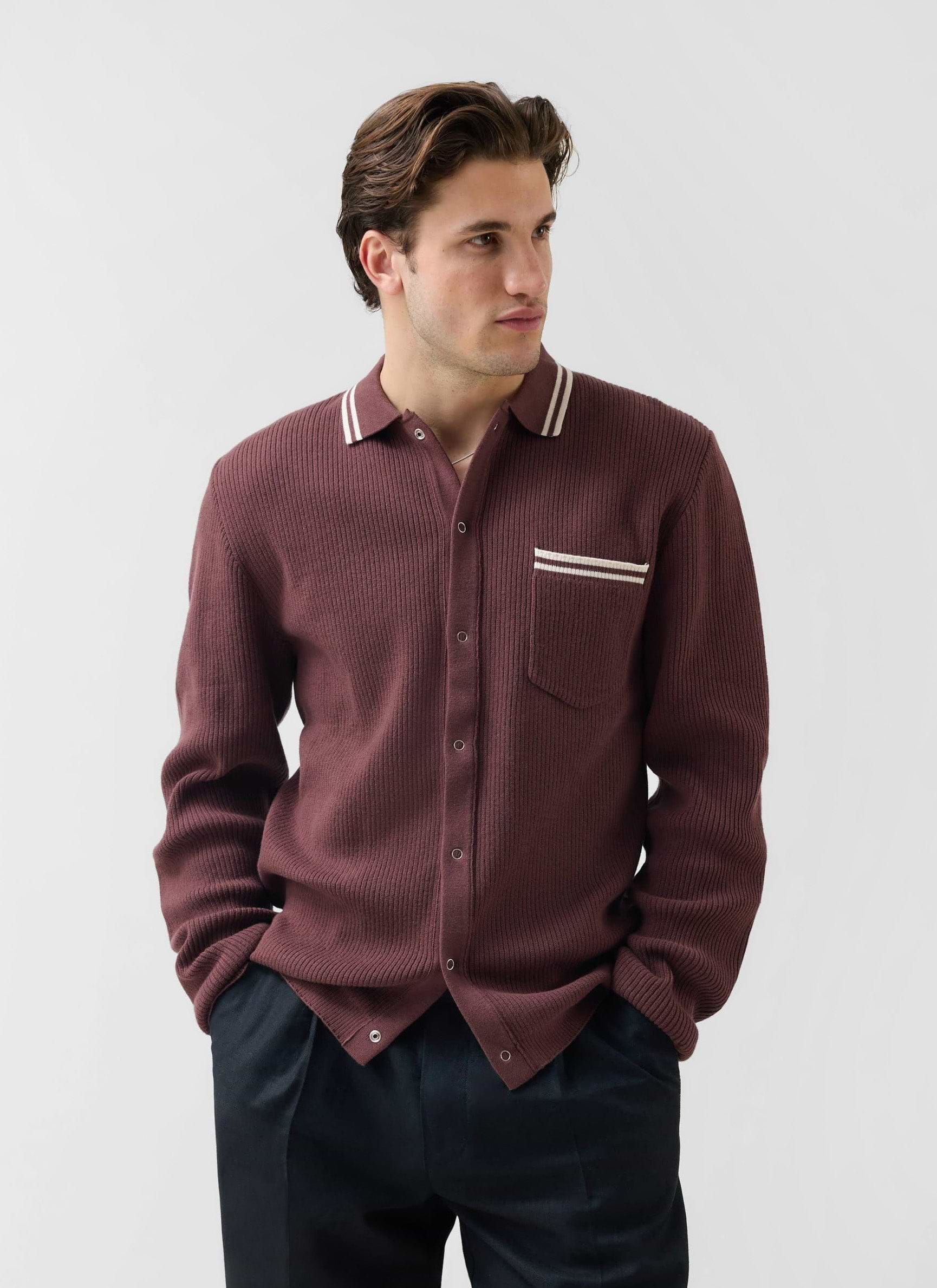 A man models the Percival Pablo long-sleeve knitted shirt in espresso brown with white tipping on the collar and pocket.