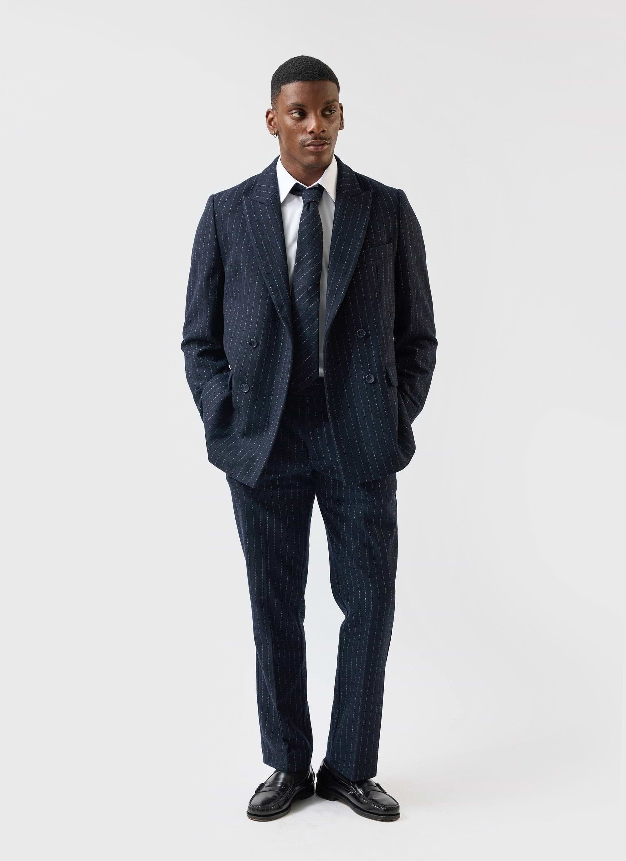 A man models the Percival Textured Stripe Double Breasted Blazer in navy, styled as a full suit against a white background.