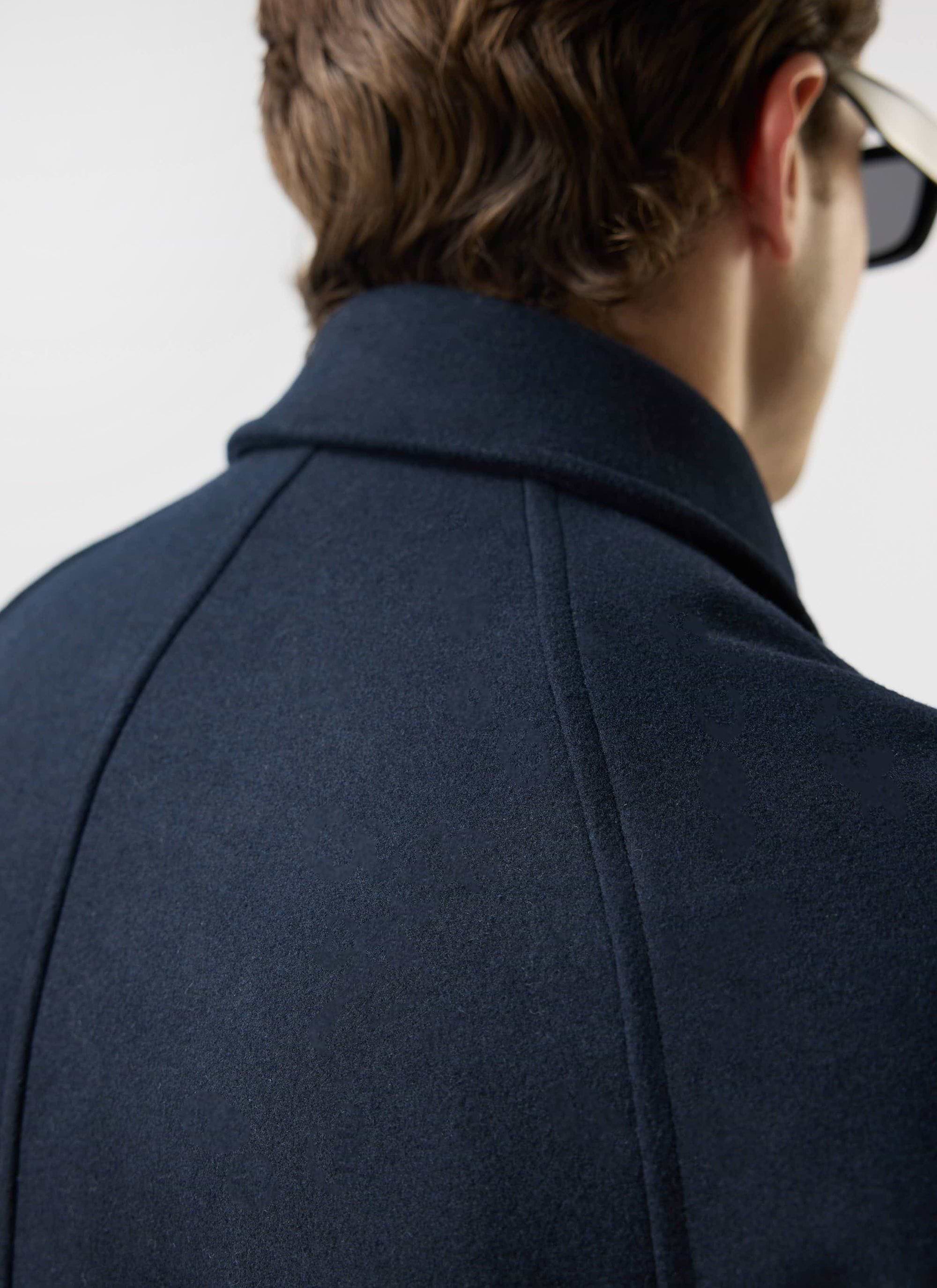 Close-up of the collar and shoulder seam detail on the navy Wool Car Coat from Percival, seen from behind a model.