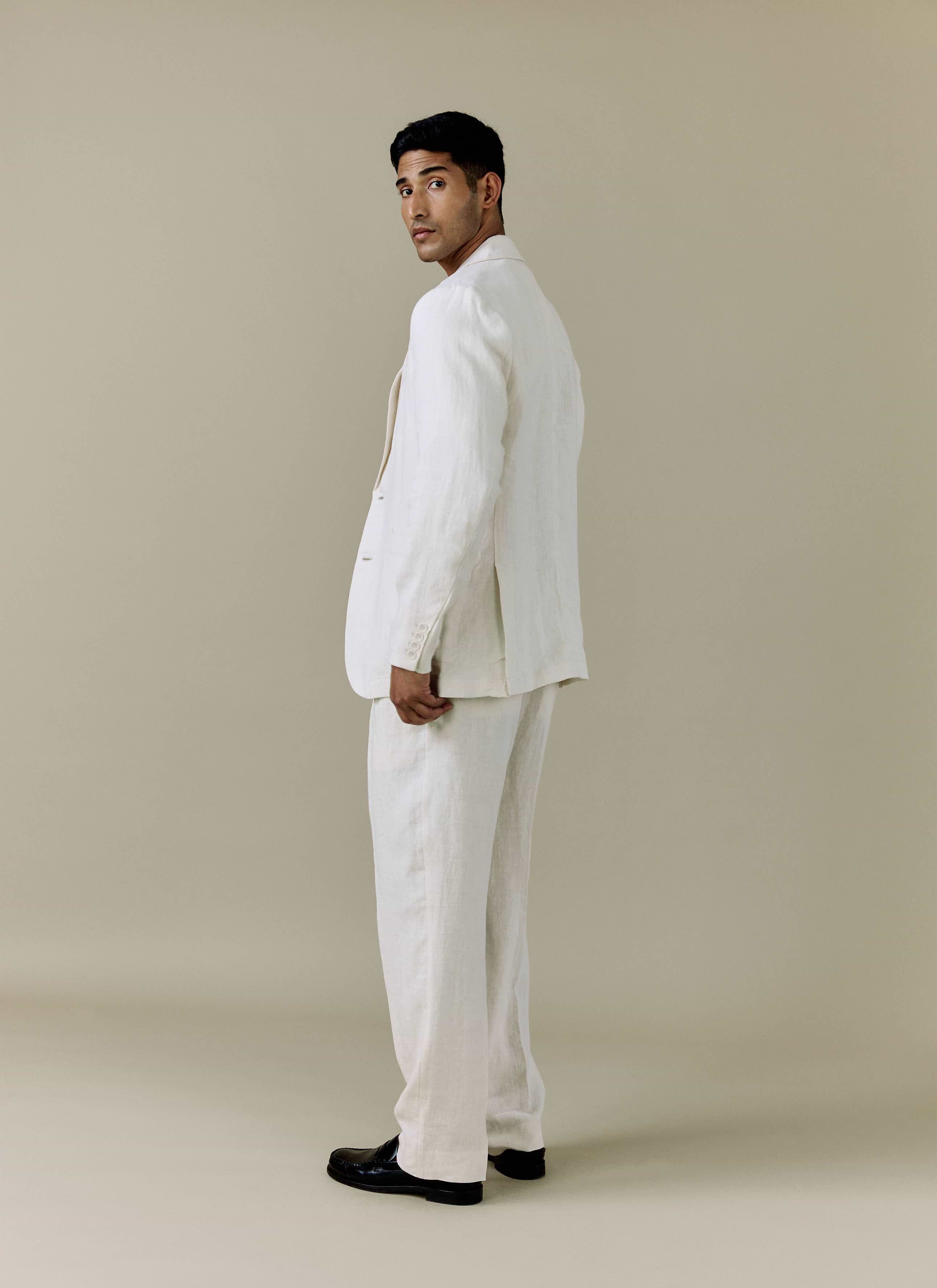 A model looks over his shoulder wearing the Percival Tailored Linen Blazer and matching trousers in cream.
