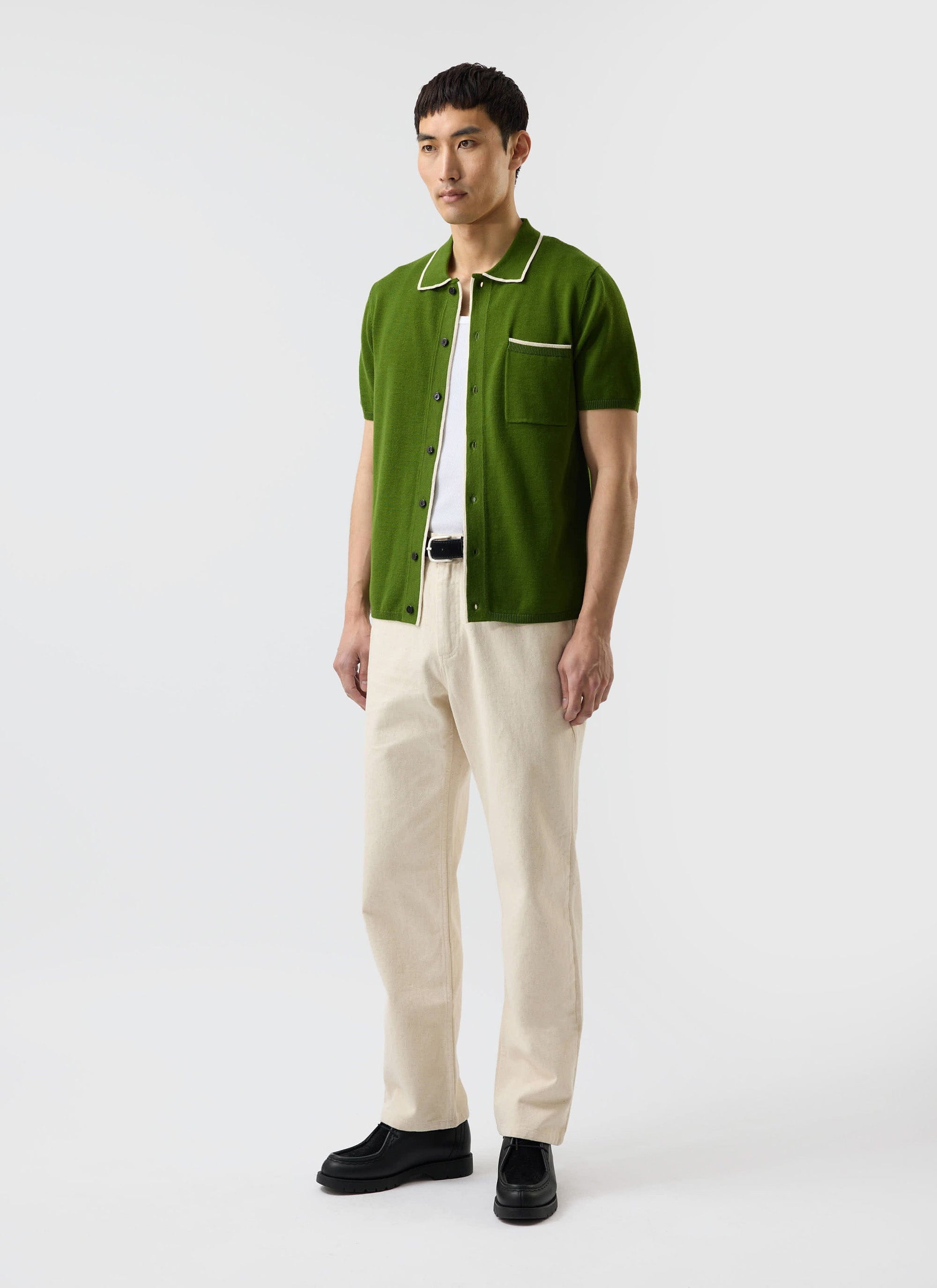 A man models the Percival Contrast Trim Shirt in forest green, a wool-blend knit with ecru detailing.